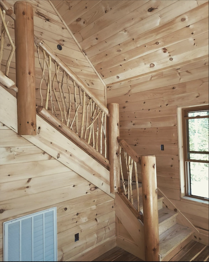 Rustic branch-style railing paired with natural wood stairs in a mountain home interior.
