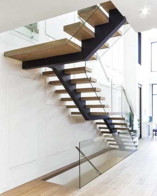 Modern interior staircase featuring custom railing with wood steps, black steel support beam, and sleek glass panels