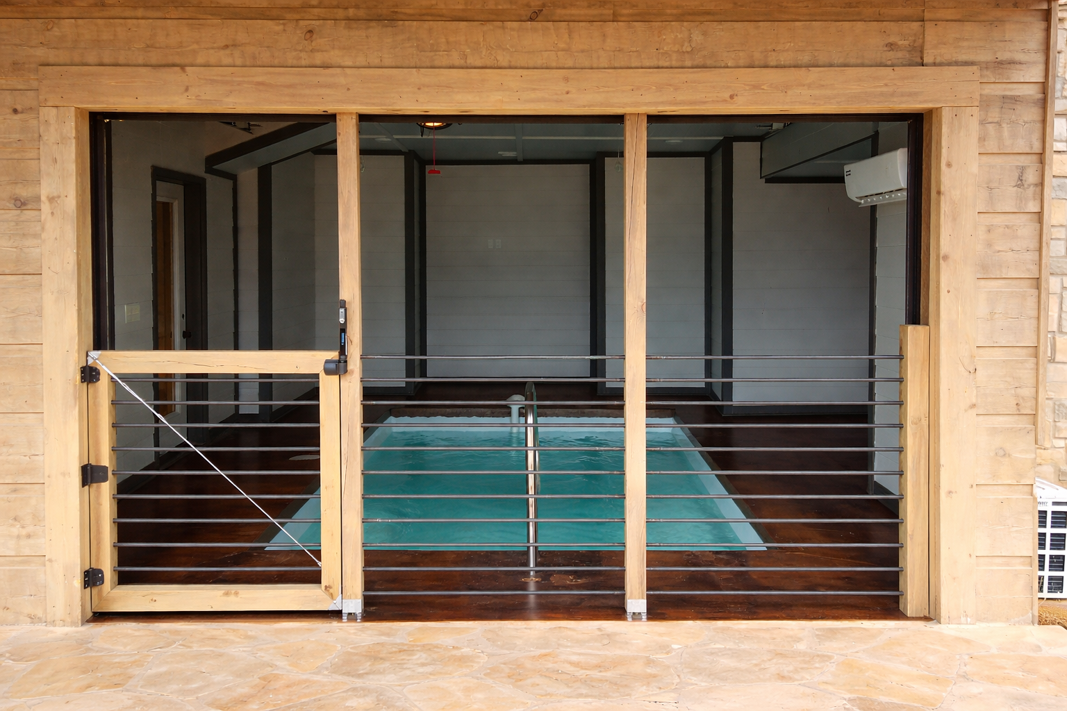 Modern horizontal cable railing on a covered wooden porch overlooking forest scenery.