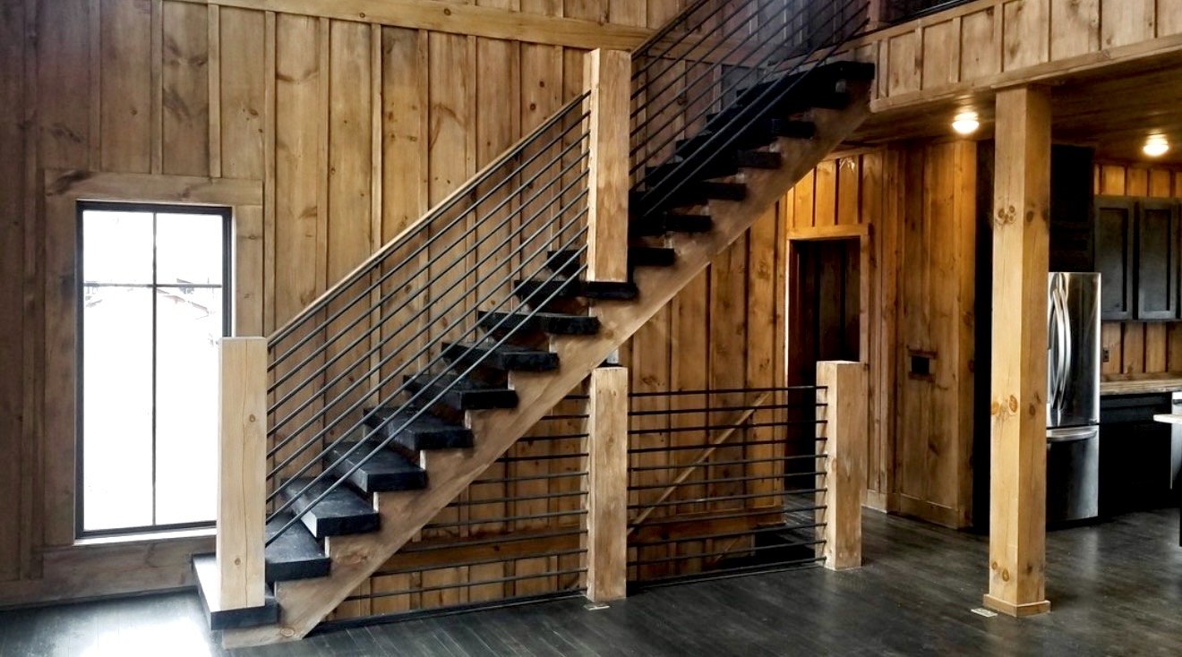 Black vertical metal railing paired with natural wood staircase in a mountain home interior.
