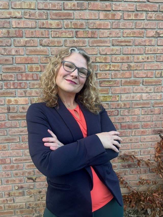 Serenity Hope Salak smiles, posing against a brick wall for a photo