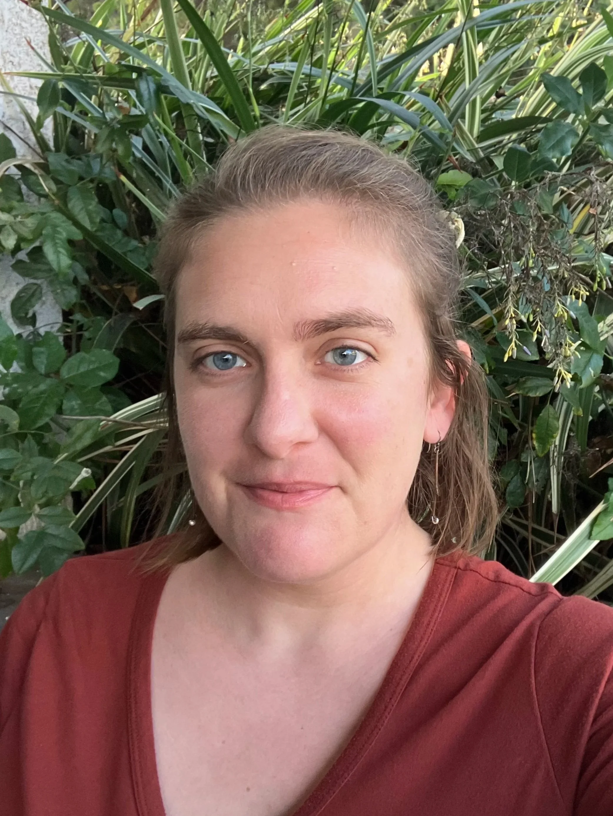 A woman standing in front of green foliage. Sarah M. Thompson, PhD