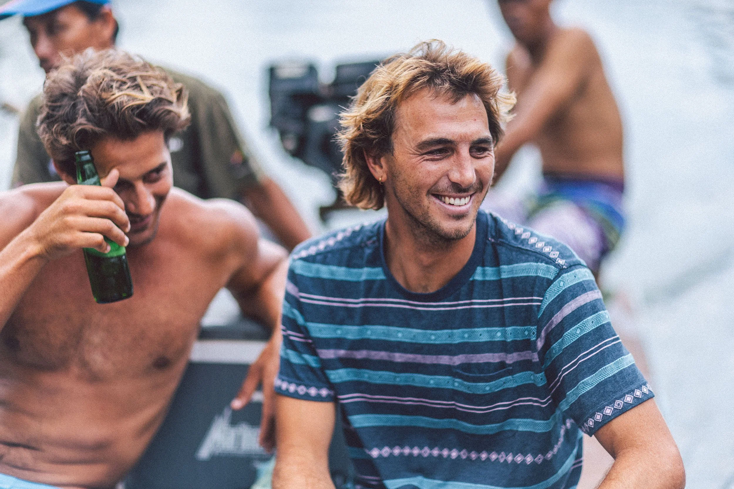People enjoying outdoor water activity, some shirtless, smiling, with water in background, casual summer attire.