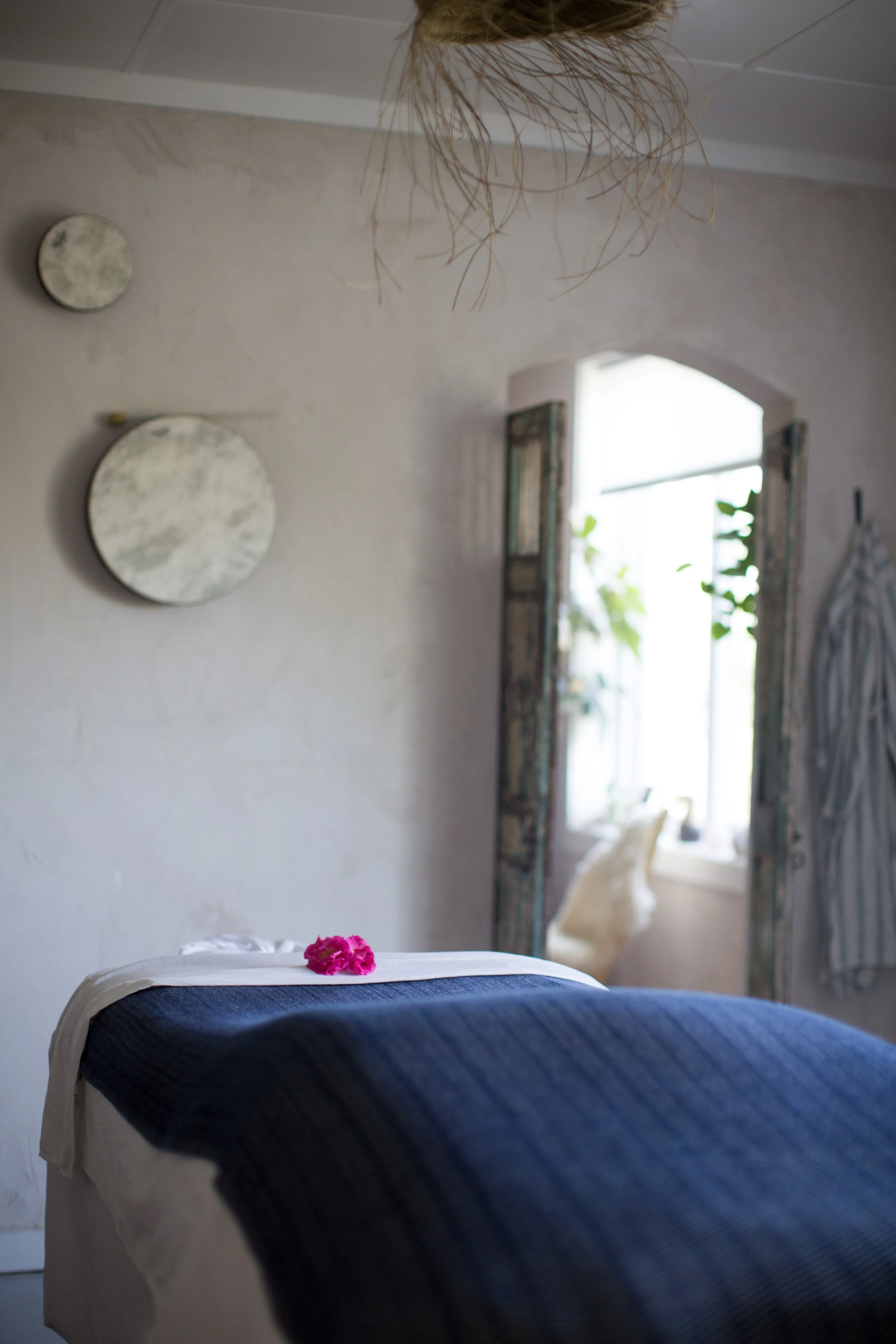 Blankets draped over a healing table in a bright studio space.