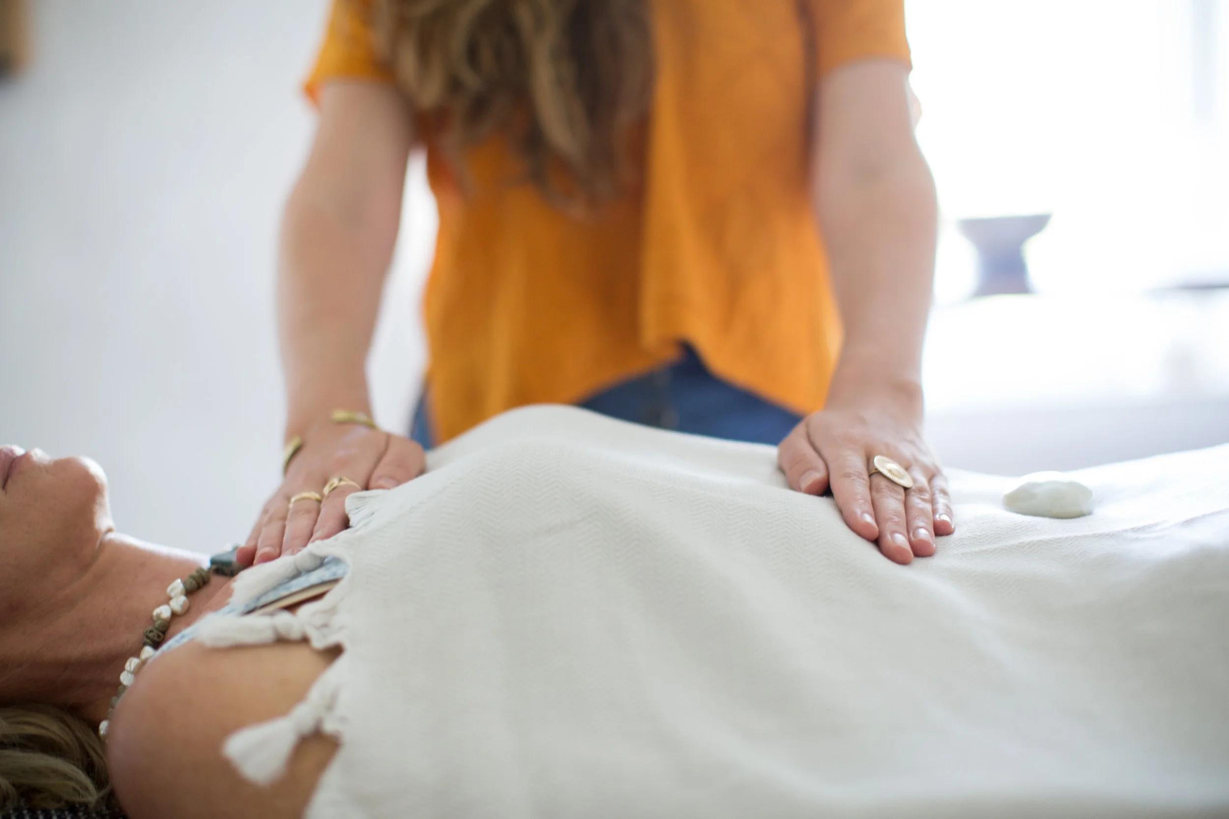 A Reiki healer safely places her hands on a client.