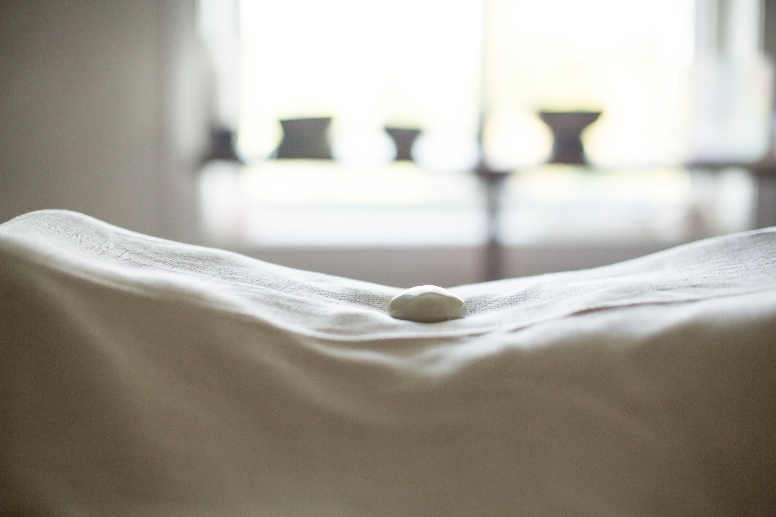 A healing table draped in a sheet with a crystal placed on top.