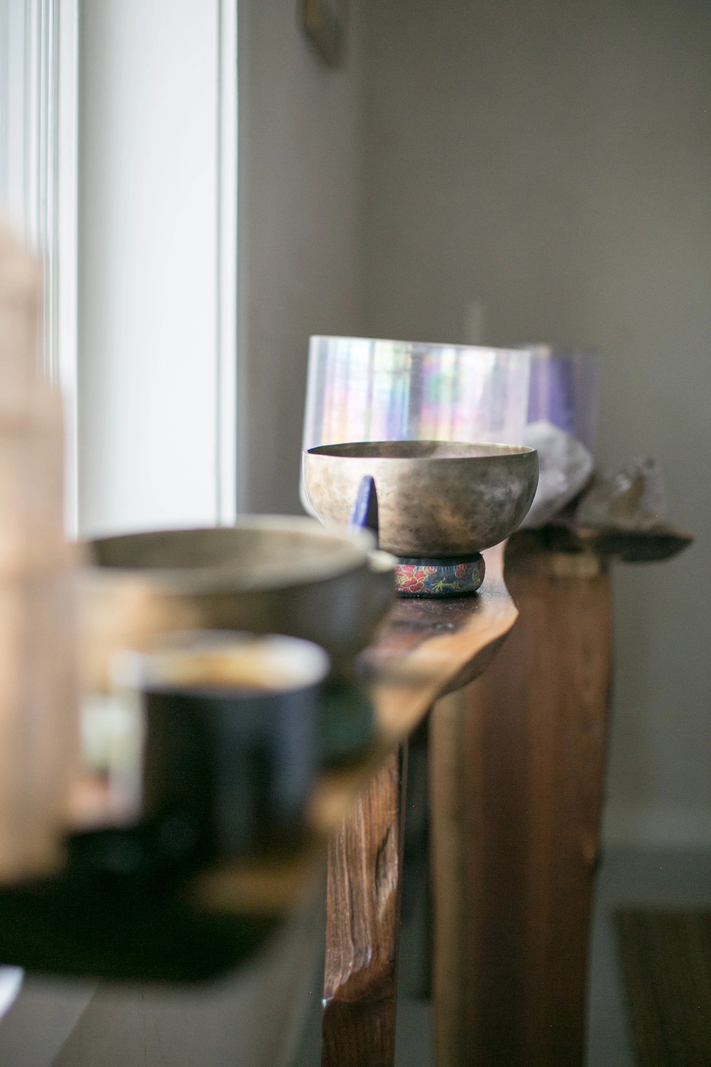 Healing bowls sit on a shelf in the sunshine.
