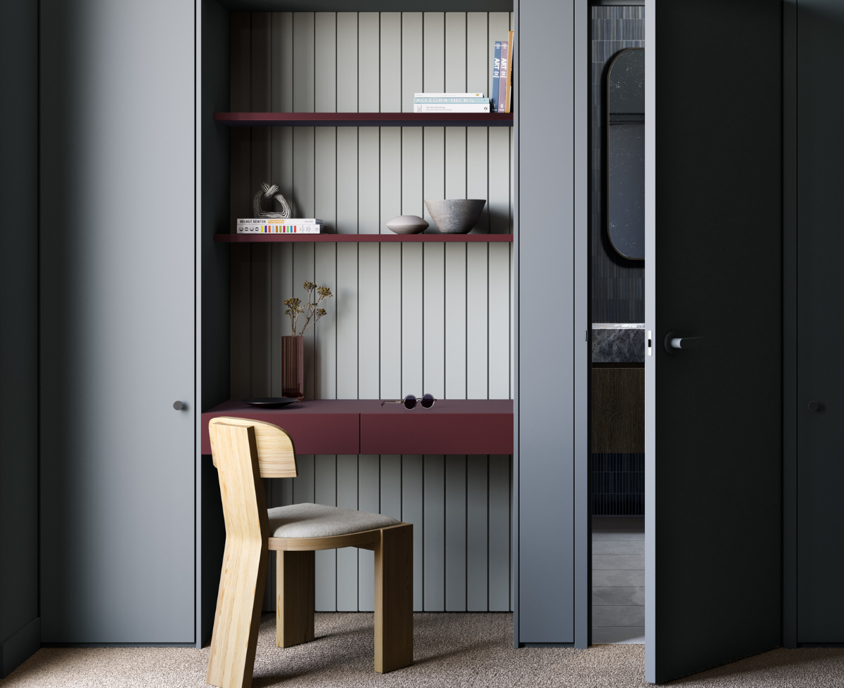 A small workspace with a wooden chair, maroon laminate desk, and built-in shelves holding books and decorative items, situated within a closet or nook.