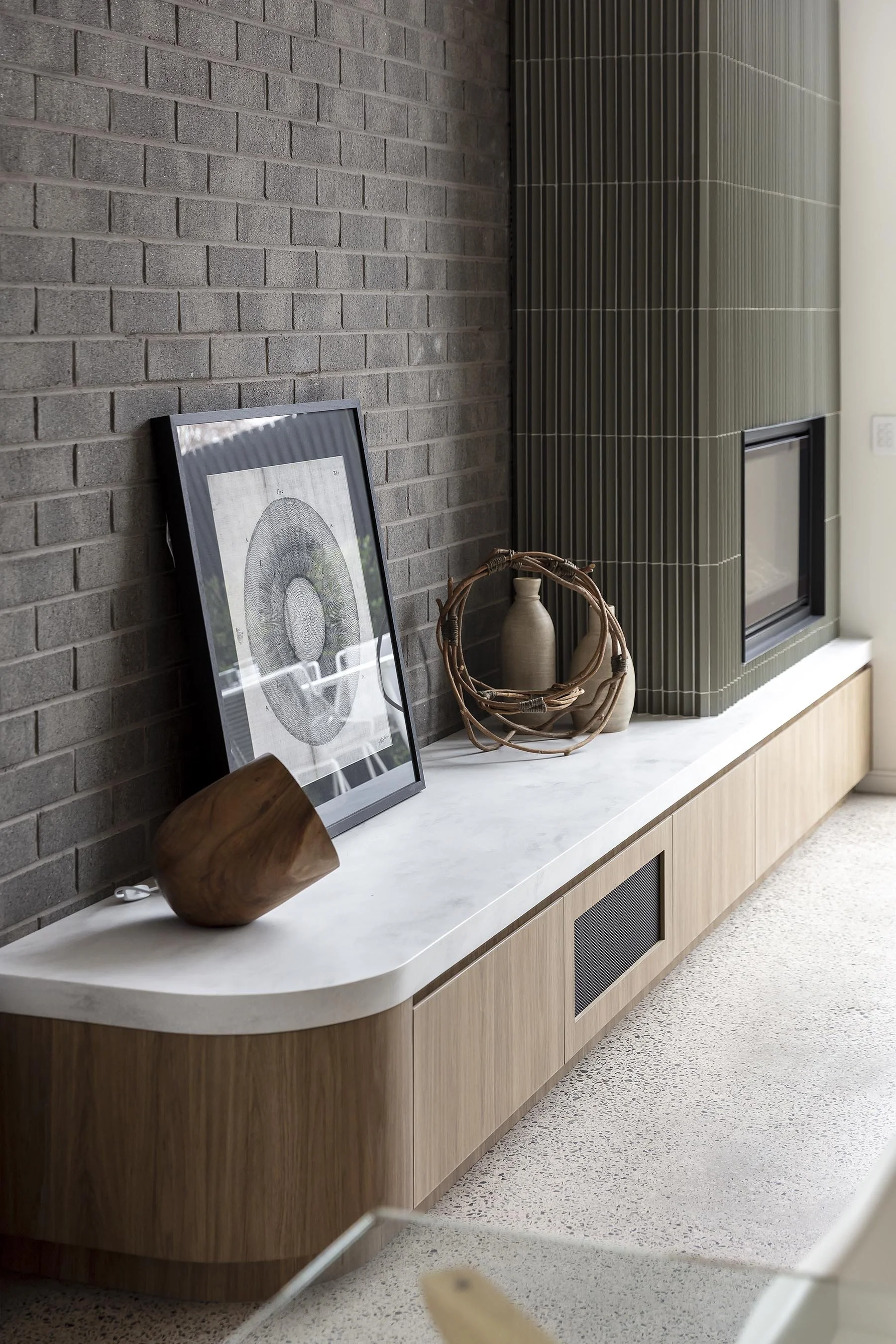 Decorative living room corian raincloud mantle with framed artwork, vases, and woven arrangements.