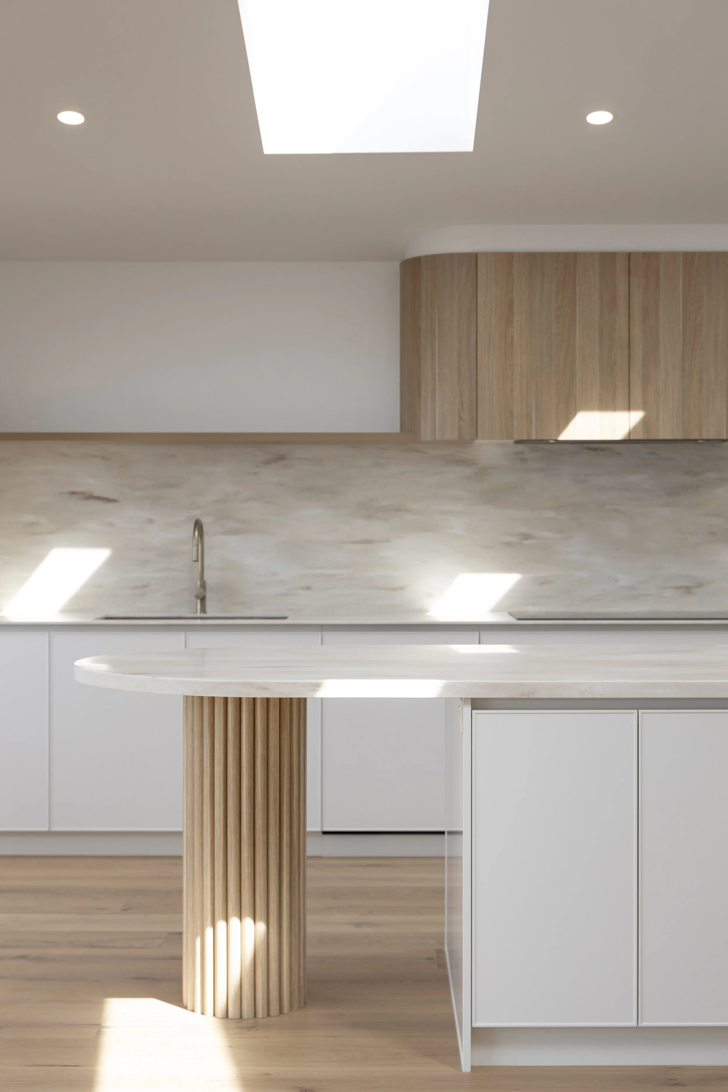 Modern kitchen with white cabinetry, light wood accents, corian witch hazel benchtop and splashback and a skylight overhead.