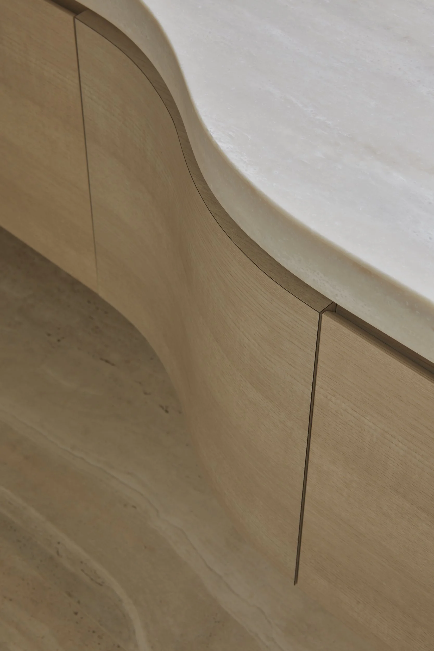 Close-up of a modern wooden cabinet with a curved design, topped with a white marble countertop.