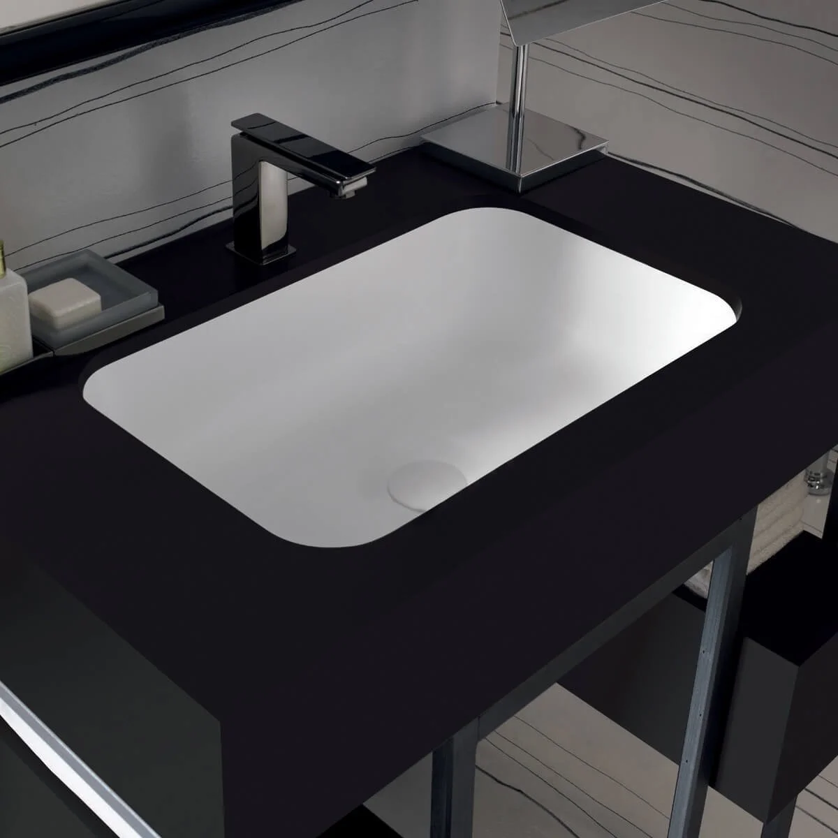 Modern black bathroom countertop with an integrated white sink, a sleek black faucet, and some toiletries on the left side.