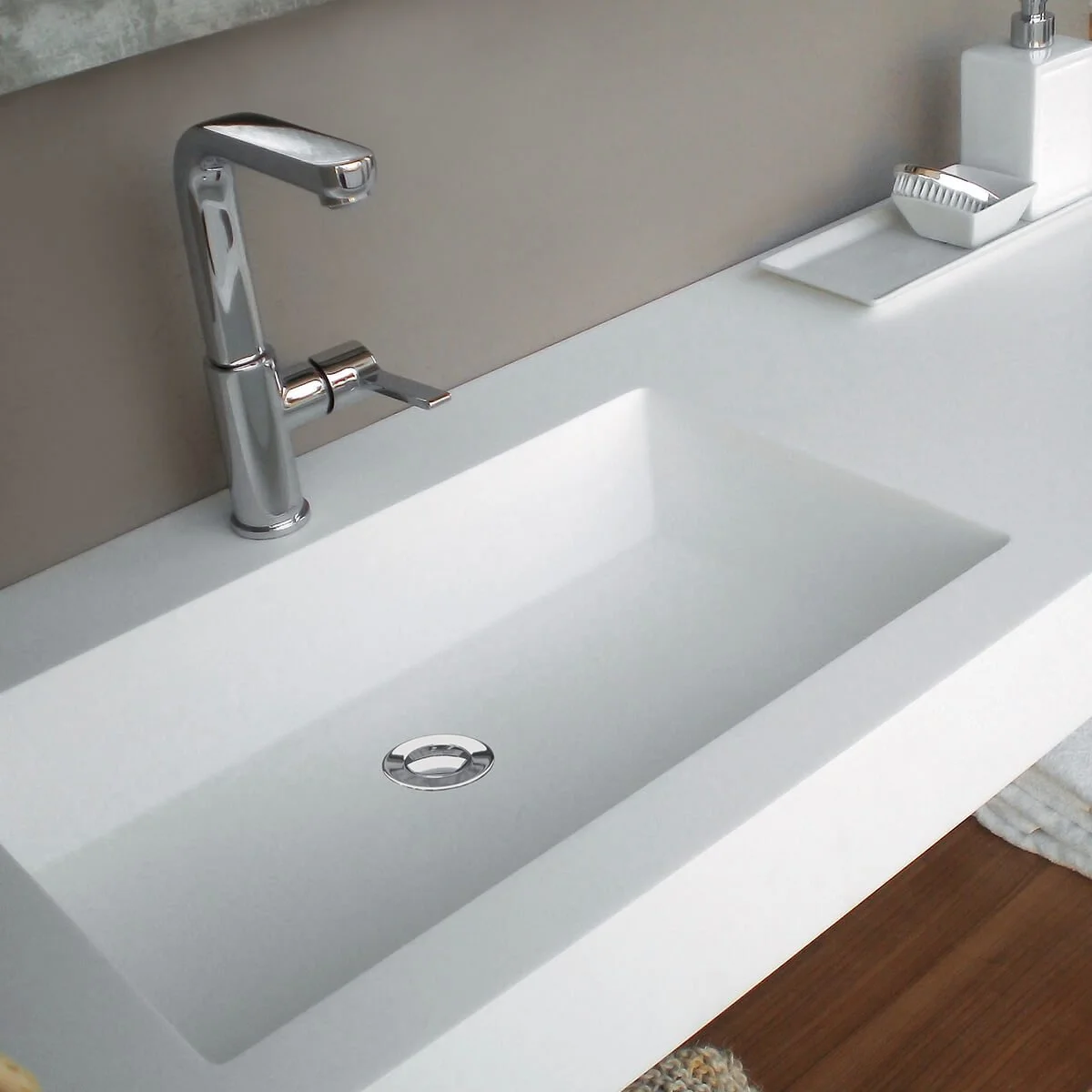 White bathroom sink with a chrome faucet, soap dish, and hand soap dispenser on the countertop.