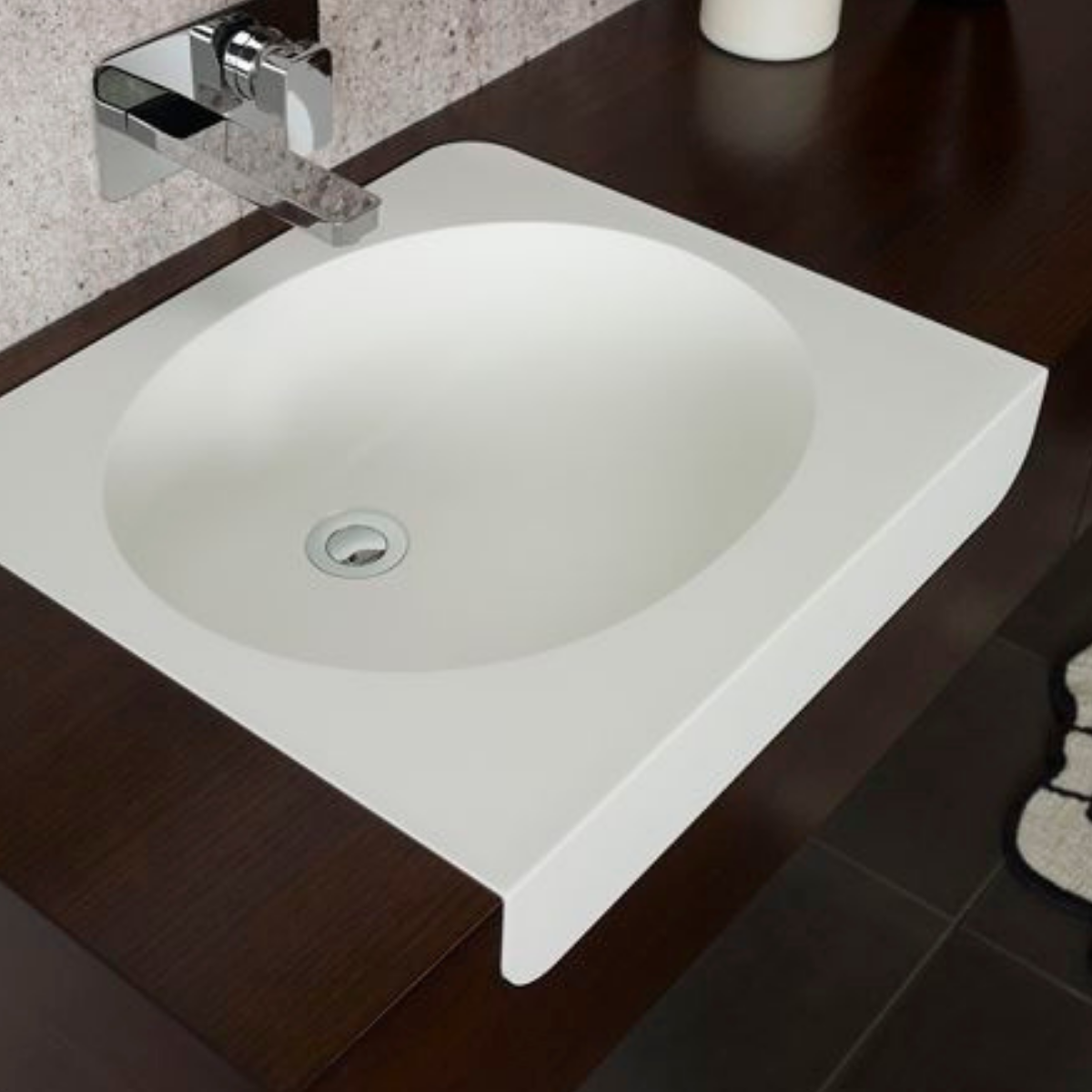 A white bathroom sink with a chrome faucet mounted on a wooden countertop.