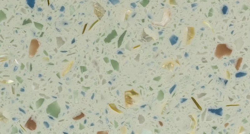 A colourful terrazzo benchtop material with irregular orange, green, yellow and off-white flecks. Meganite Kauai Beach