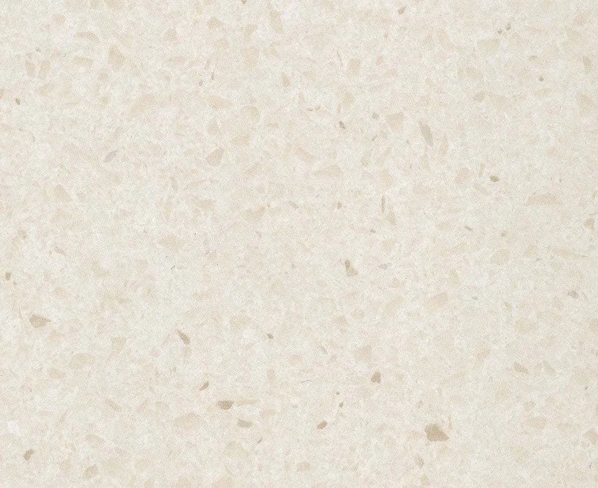 Light beige speckled textured surface, likely a close-up of a stone or countertop material.
