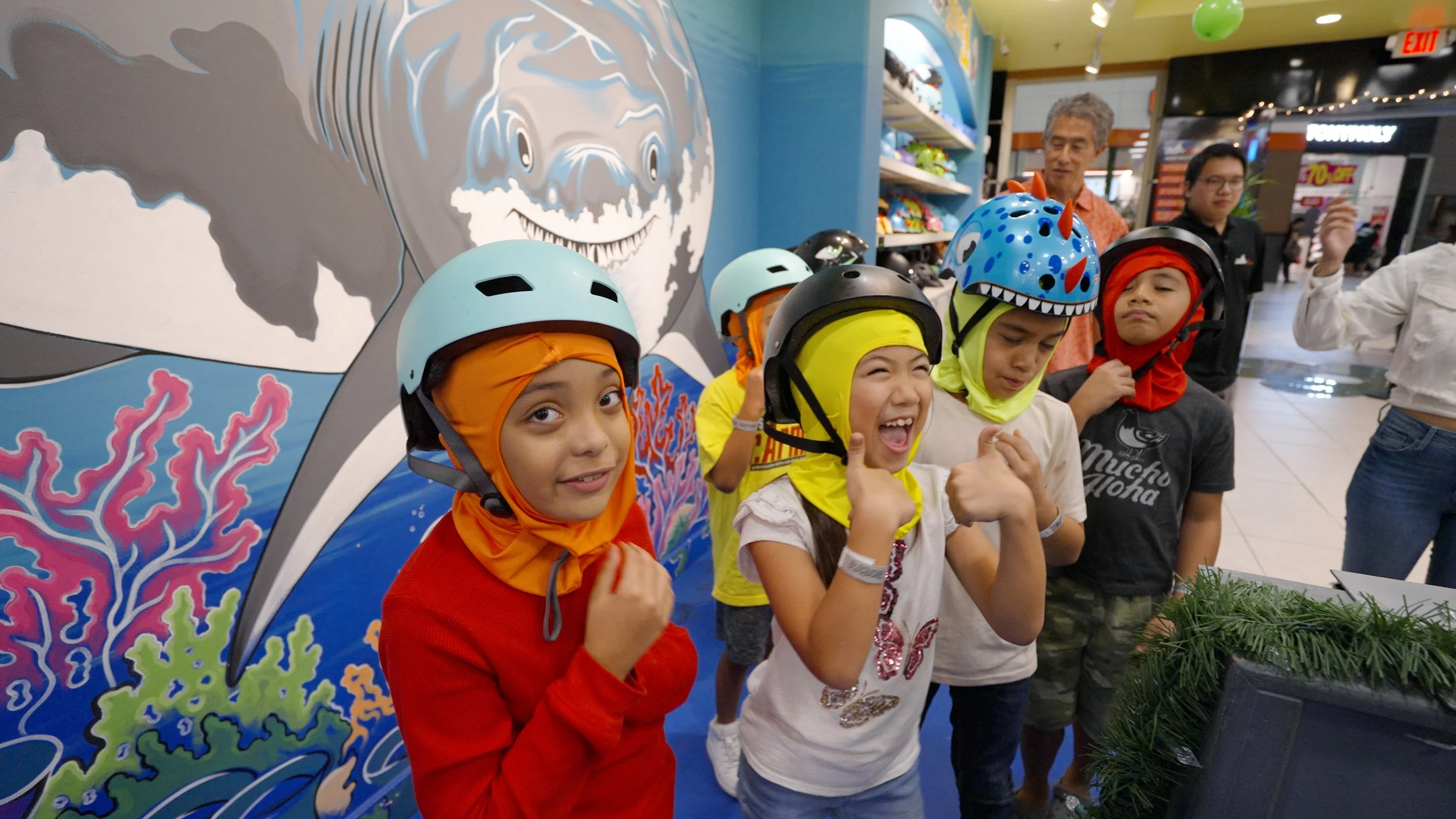 Group of kids in helmets and colorful clothing, smiling and excited for a party.