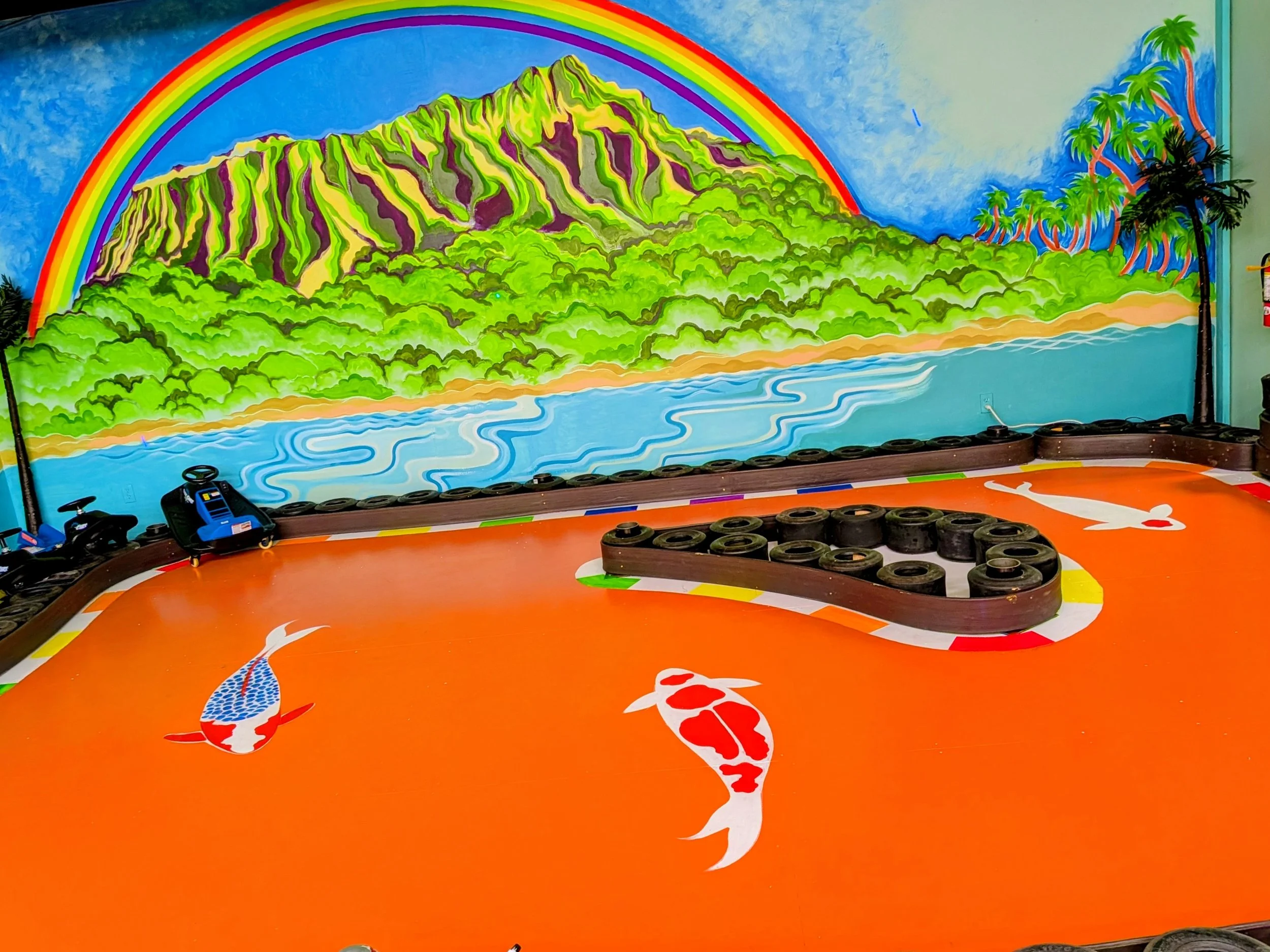 Indoor go-kart track for little children, decorated with a bright rainbow and fish