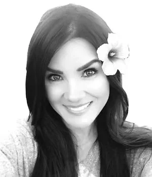 Black and white photo of a woman smiling with a flower in her hair.