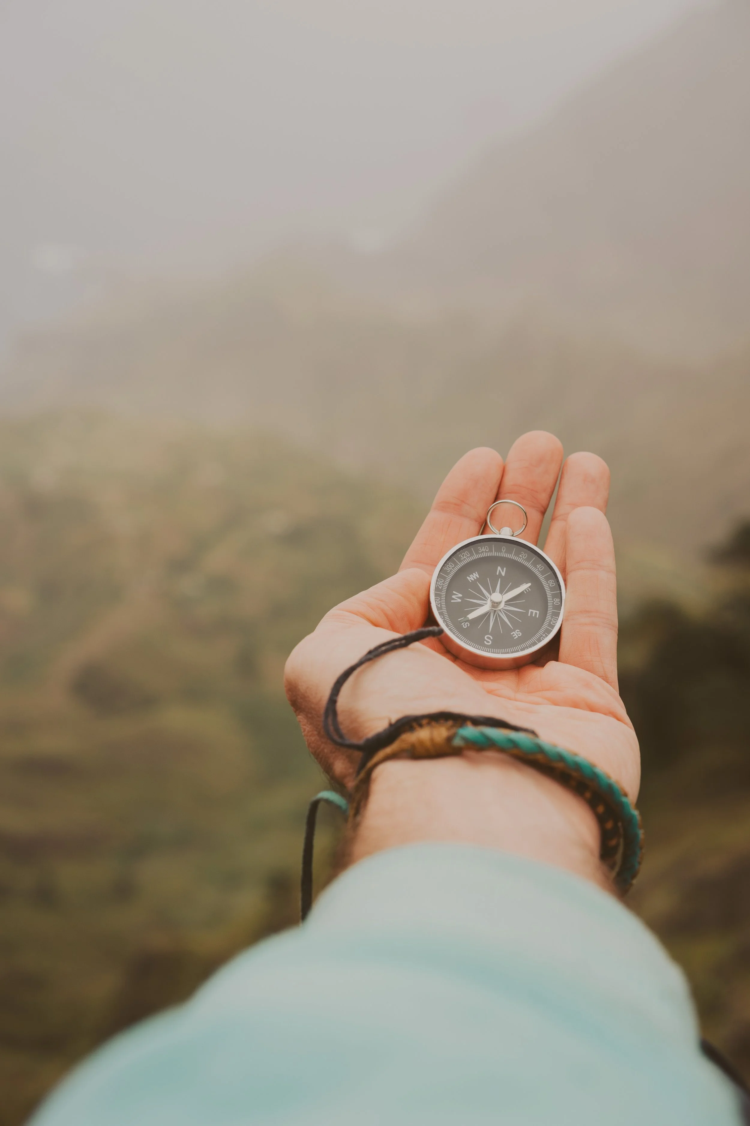 Pastor finding direction clarity coaching consulting missions holding a compass in foggy outdoor setting.