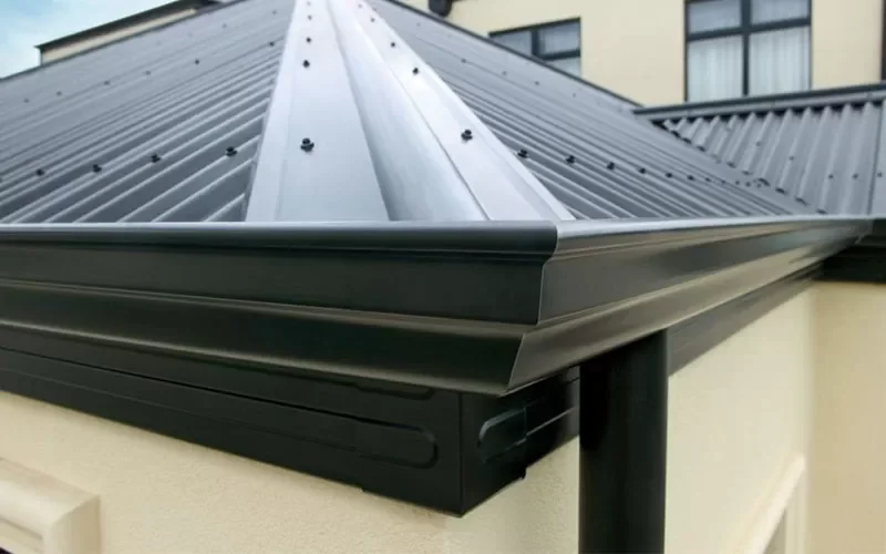 Close-up view of a black metal roof with a gutter system attached to the edge of a building.