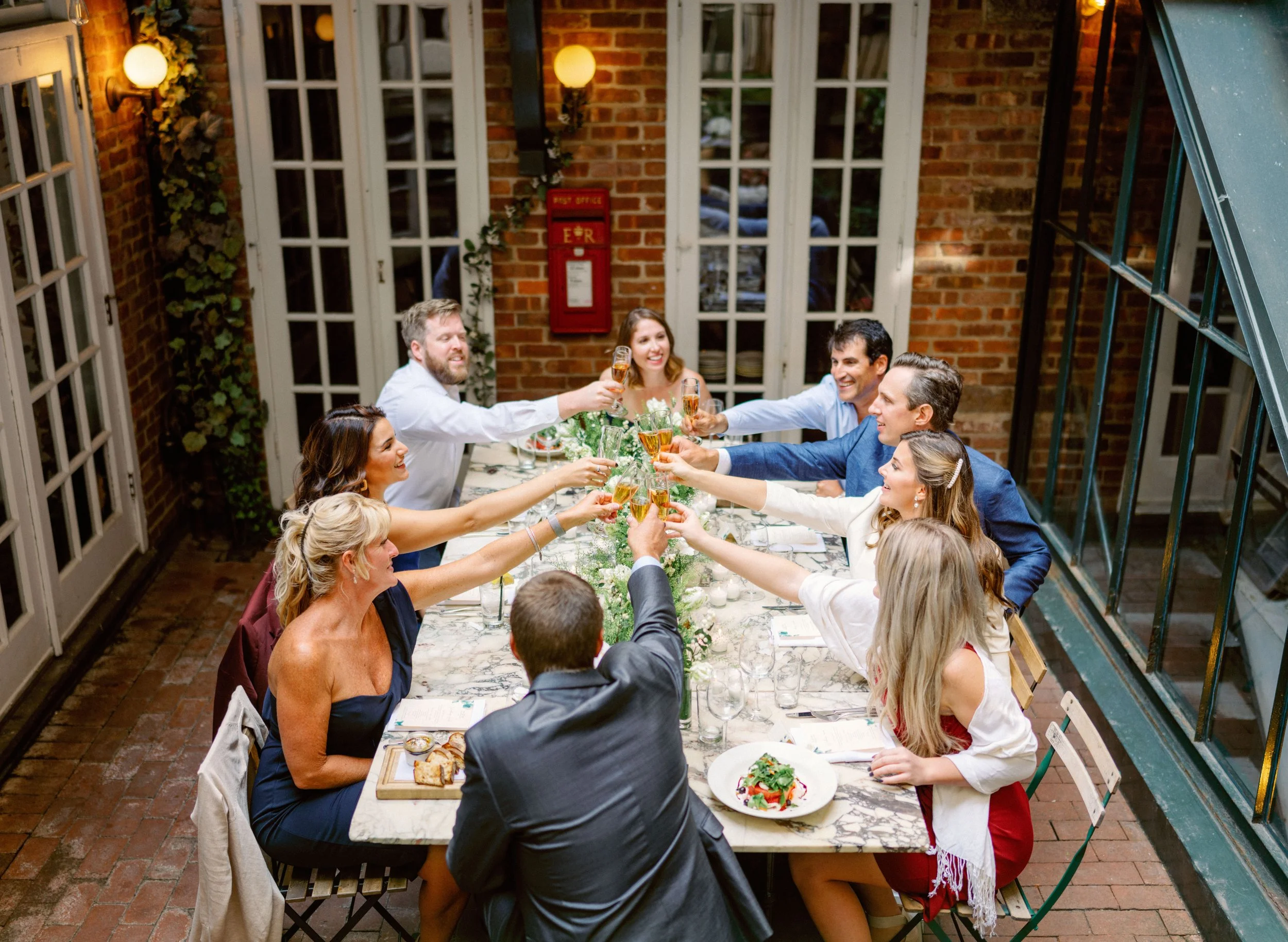 Group of friends celebrating with clinking glasses at a dinner party indoors