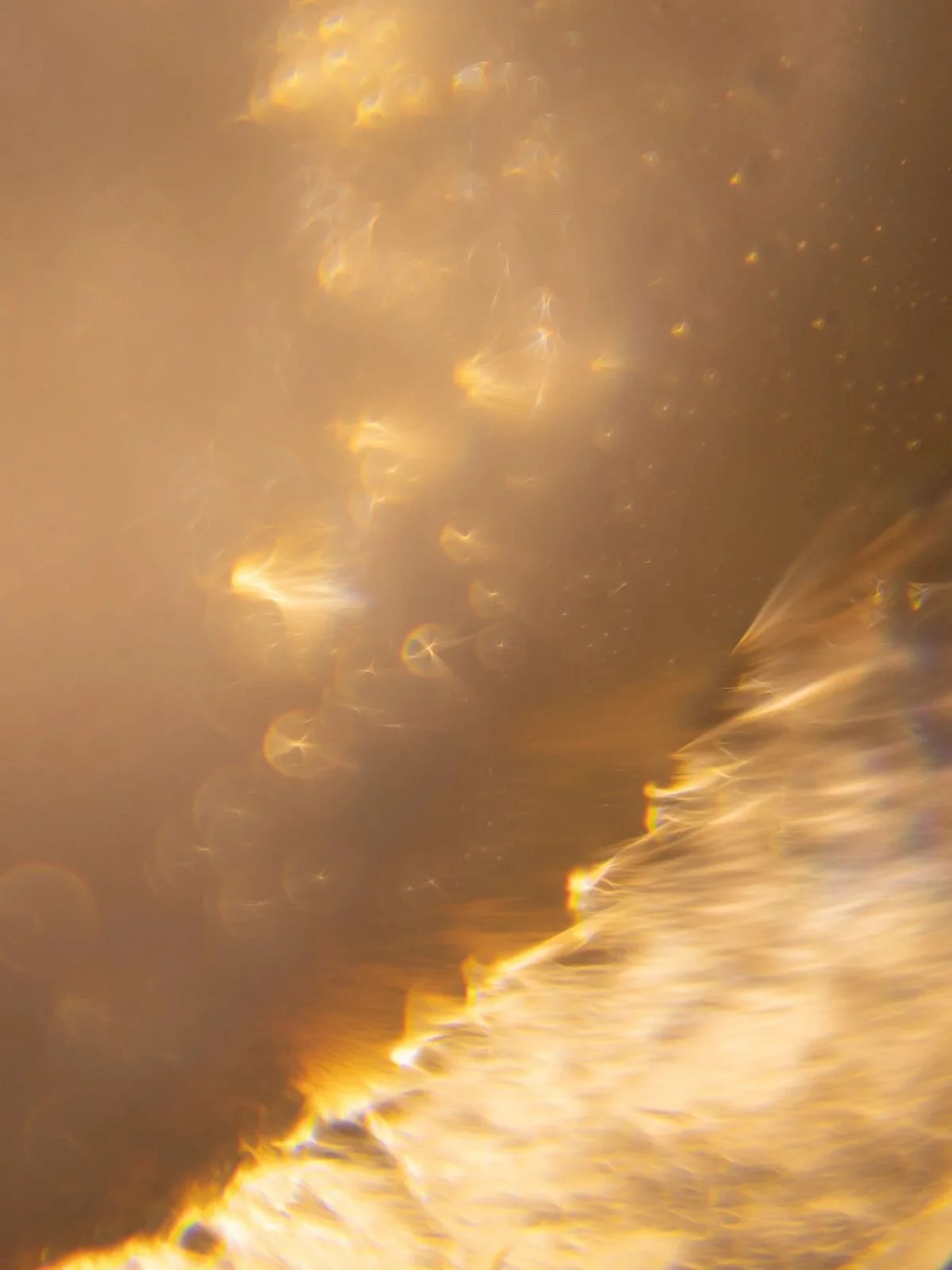 Close-up of a shiny, metallic gold surface with light reflections and some texture.