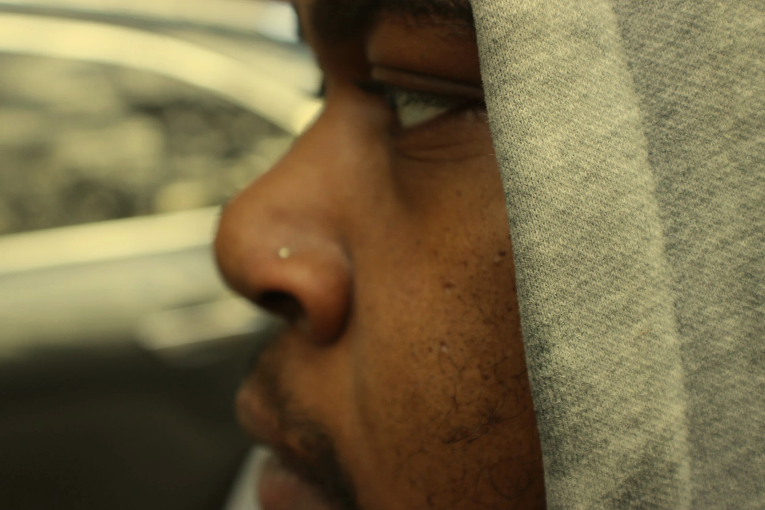 Close-up of a person's face in profile, wearing glasses and a gray hoodie.