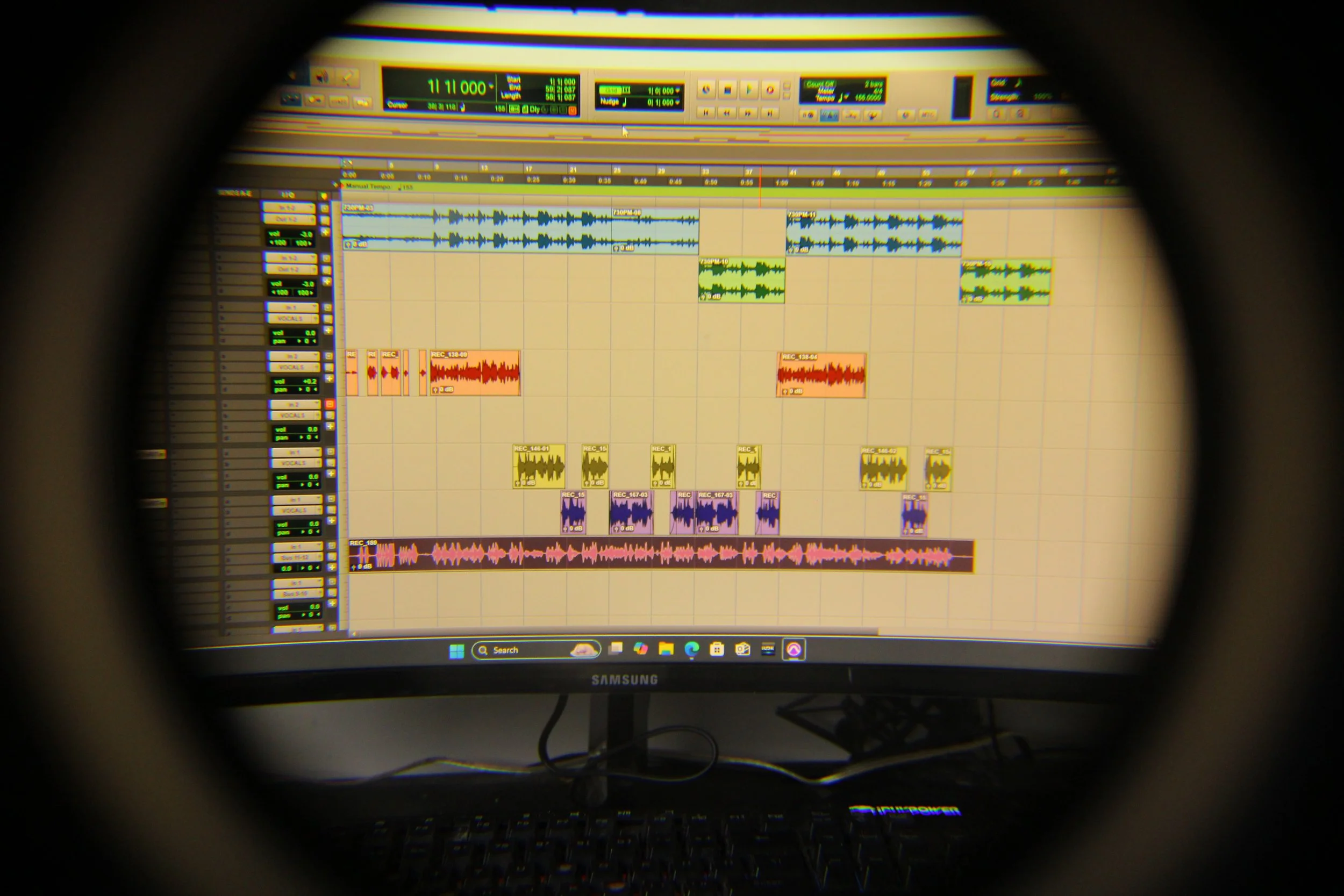 Computer screen displaying digital audio workstation (DAW) with multiple track waveforms in various colors, used for music editing or production.