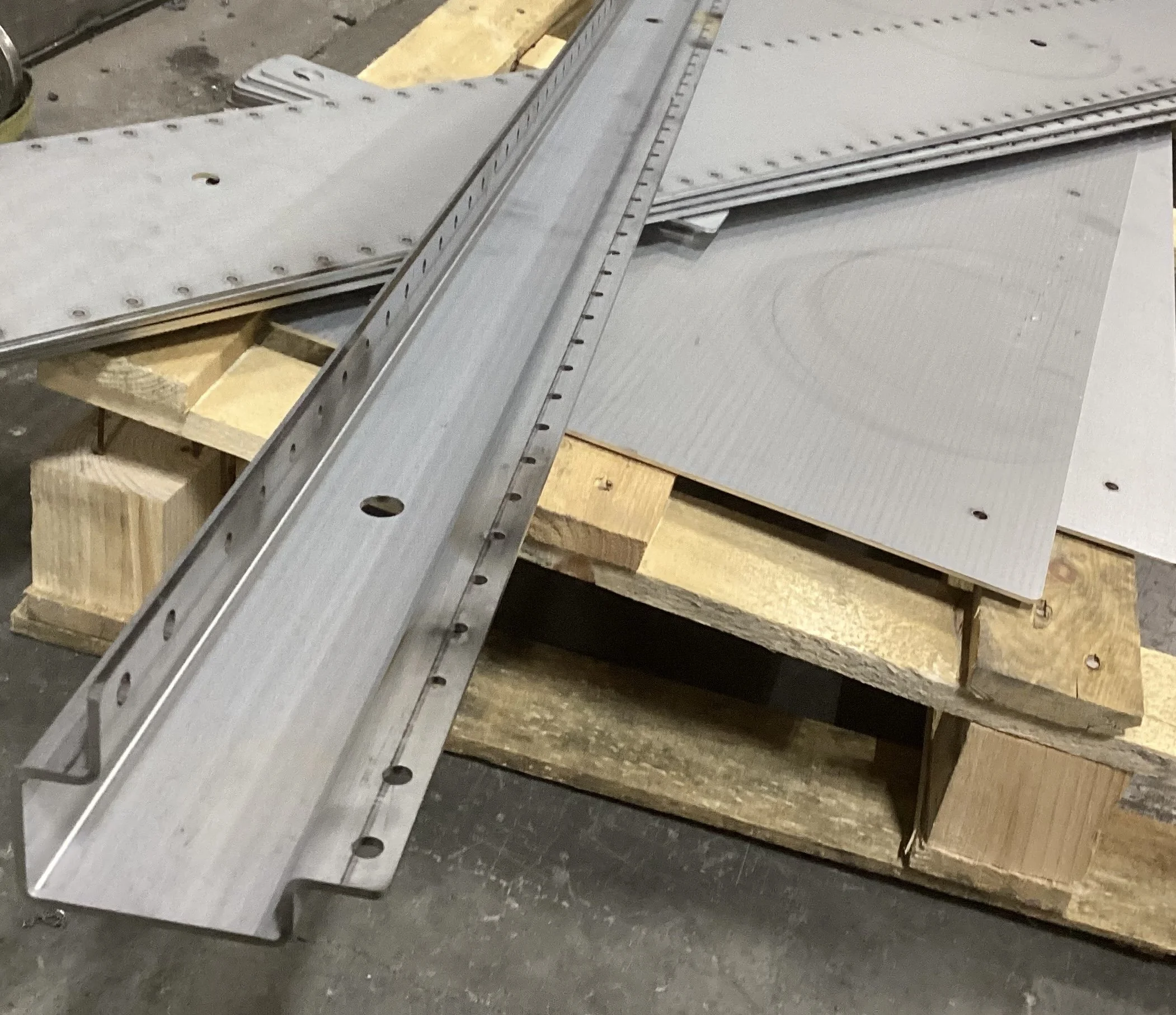 Metal molding and framing components laid out on wooden pallets in a workshop or construction setting.