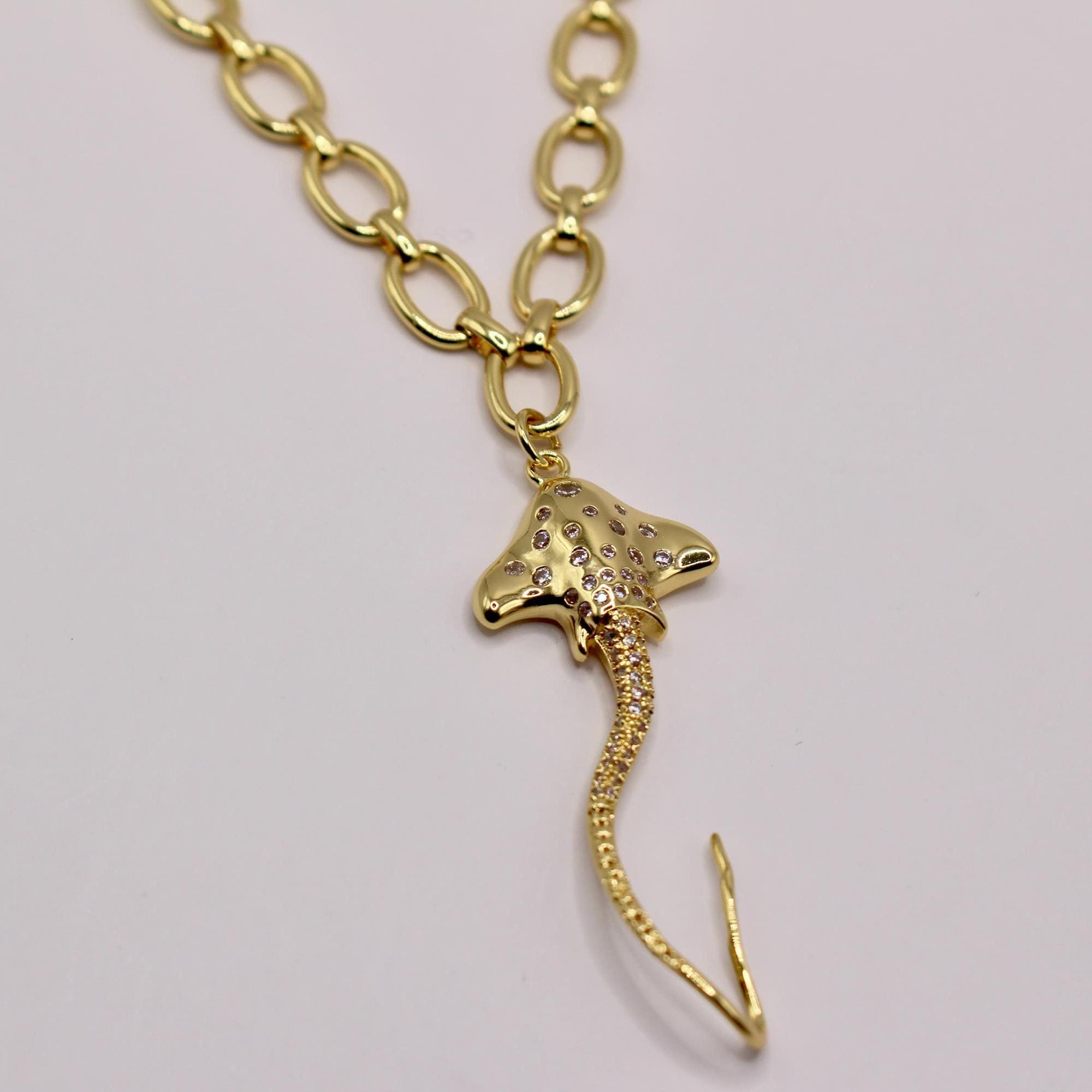 Gold necklace with a pendant shaped like a stingray with embedded crystals.