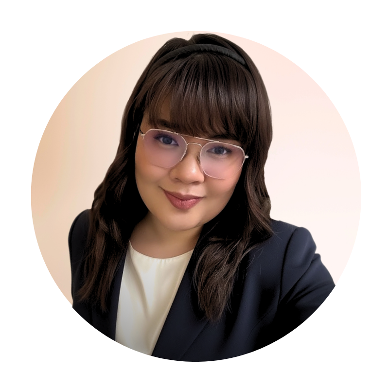A woman with shoulder-length brown hair, wearing glasses, a navy blazer, and a white top, smiling at the camera.