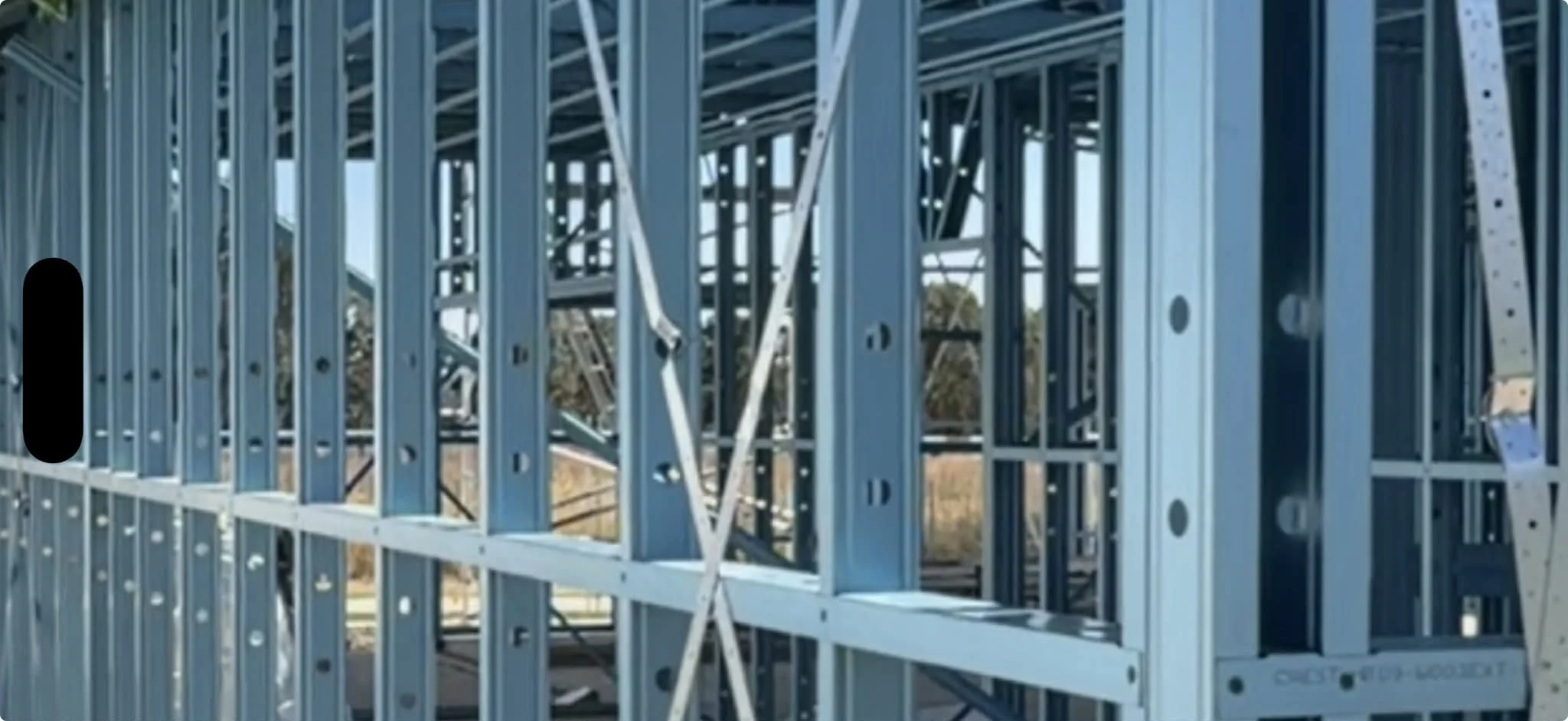 Steel framing structure of a building under construction, with blue-painted metal studs and beams.