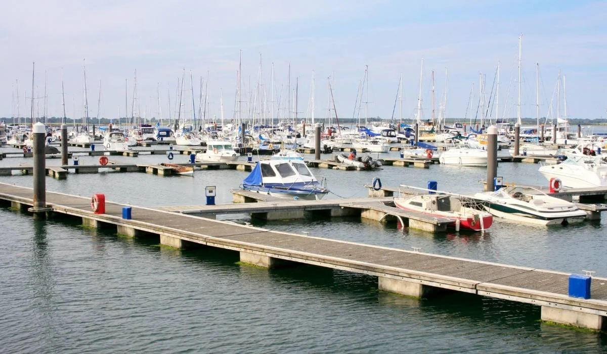 marina in Malahide  with multiple boats docked at wooden piers on calm water, with a bright and clear sky.
