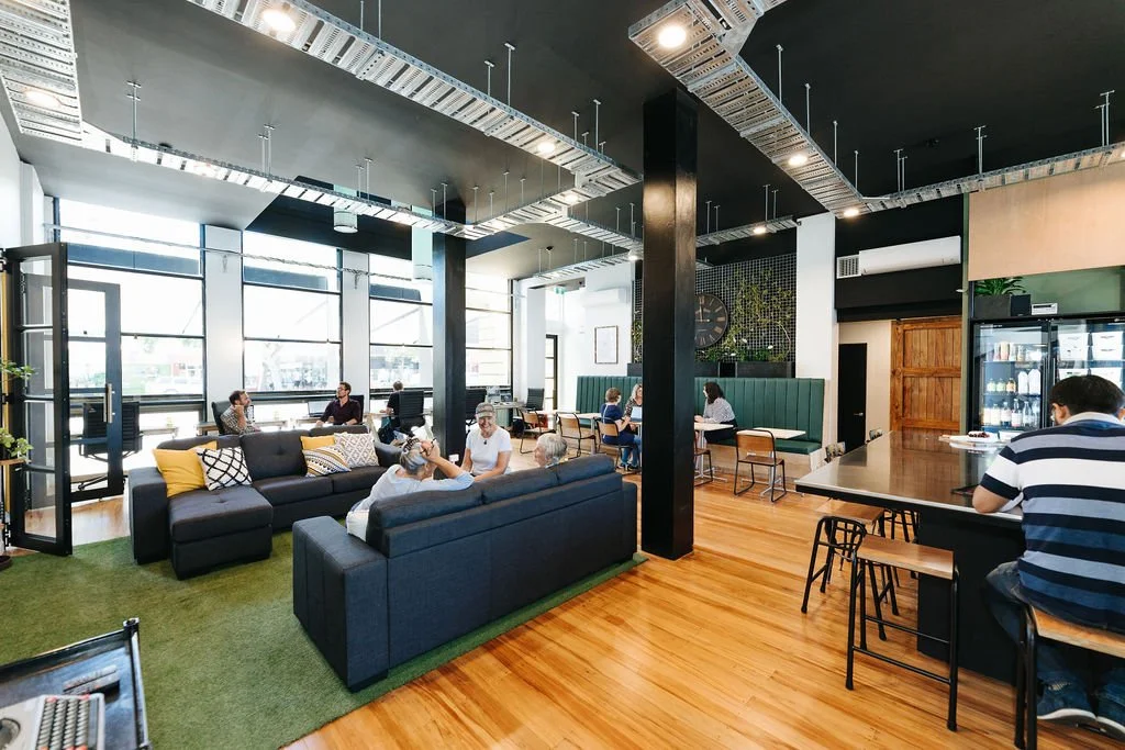 Interior of The Bank communal workspace in The Business Hive coworking space in Oamaru with cosy sitting area, wooden floor and lots of natural light.
