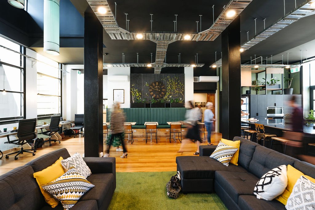 Interior of The Bank communal workspace in The Business Hive coworking space in Oamaru, a modern open space with large windows and a communal kitchen and sitting area.