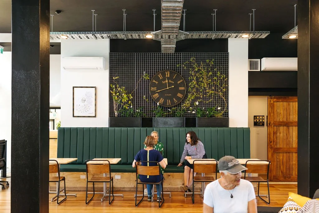 Interior of The Bank, the communal workspace at The Business Hive in Oamaru with people sitting at tables talking.