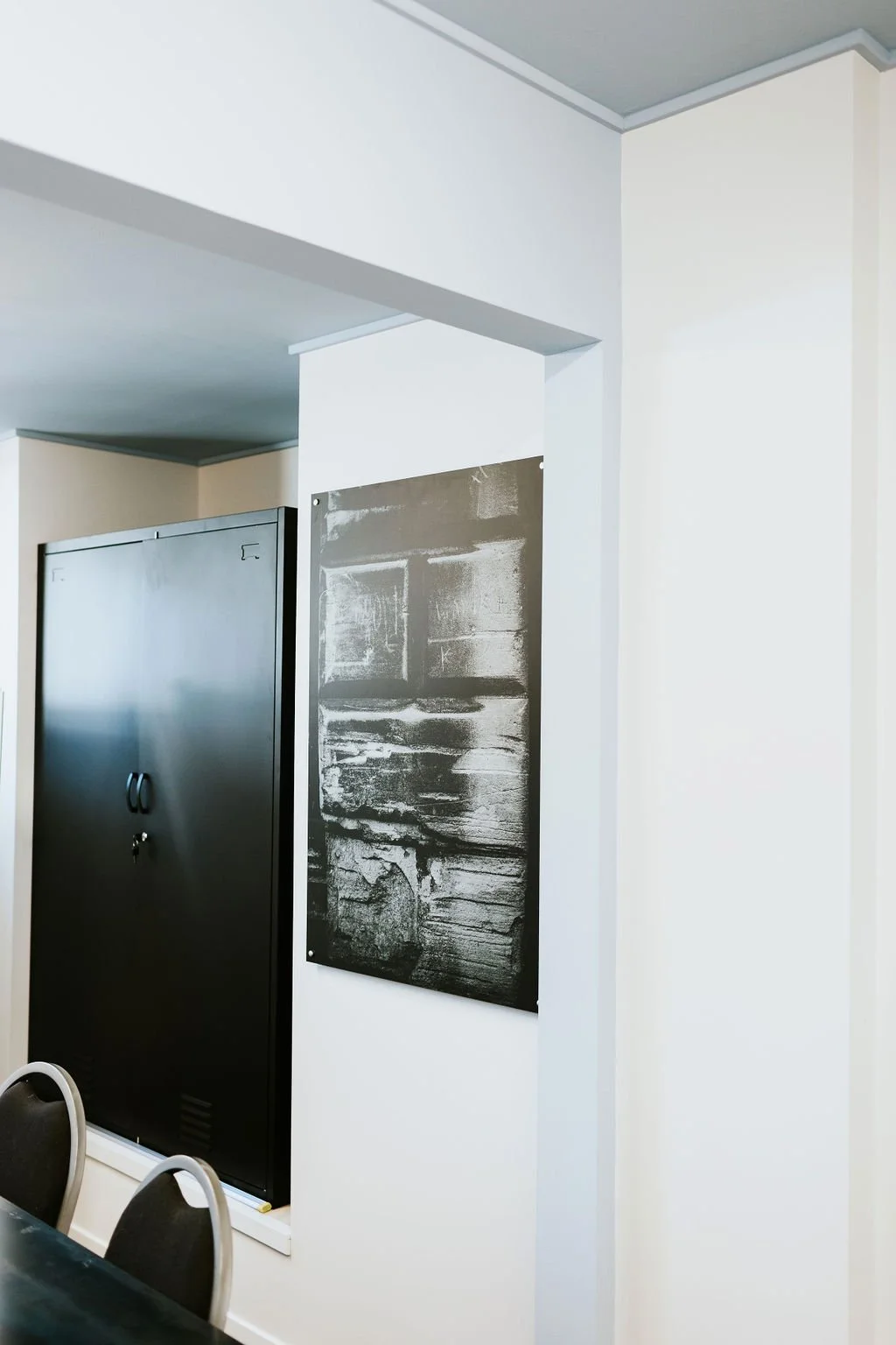 A black locker, a piece of art with black and white abstract designs, and a partial view of some chairs in The Foundry meeting room at The Business Hive.