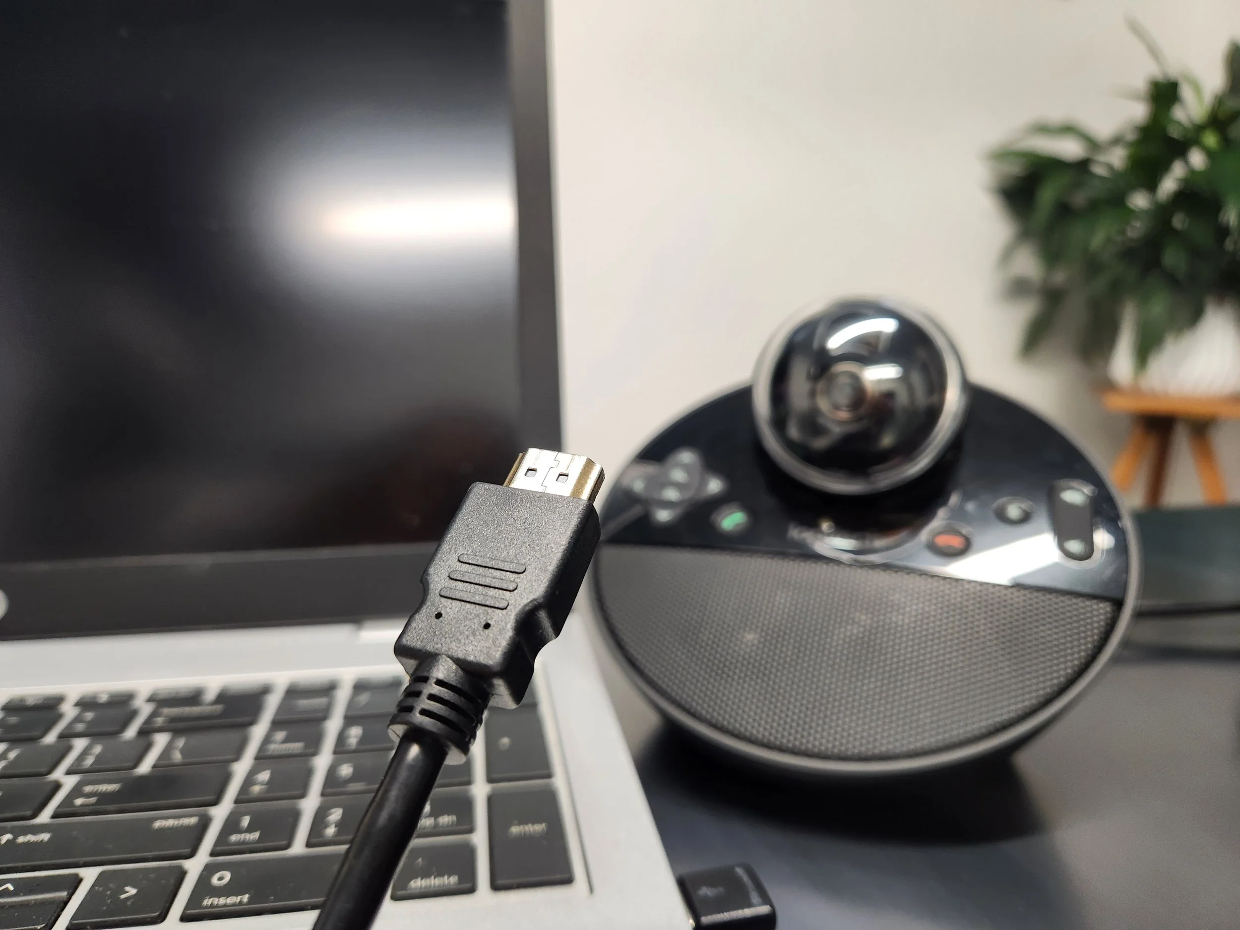 Video conferencing setup with laptop, HDMI cable and speaker with camera
