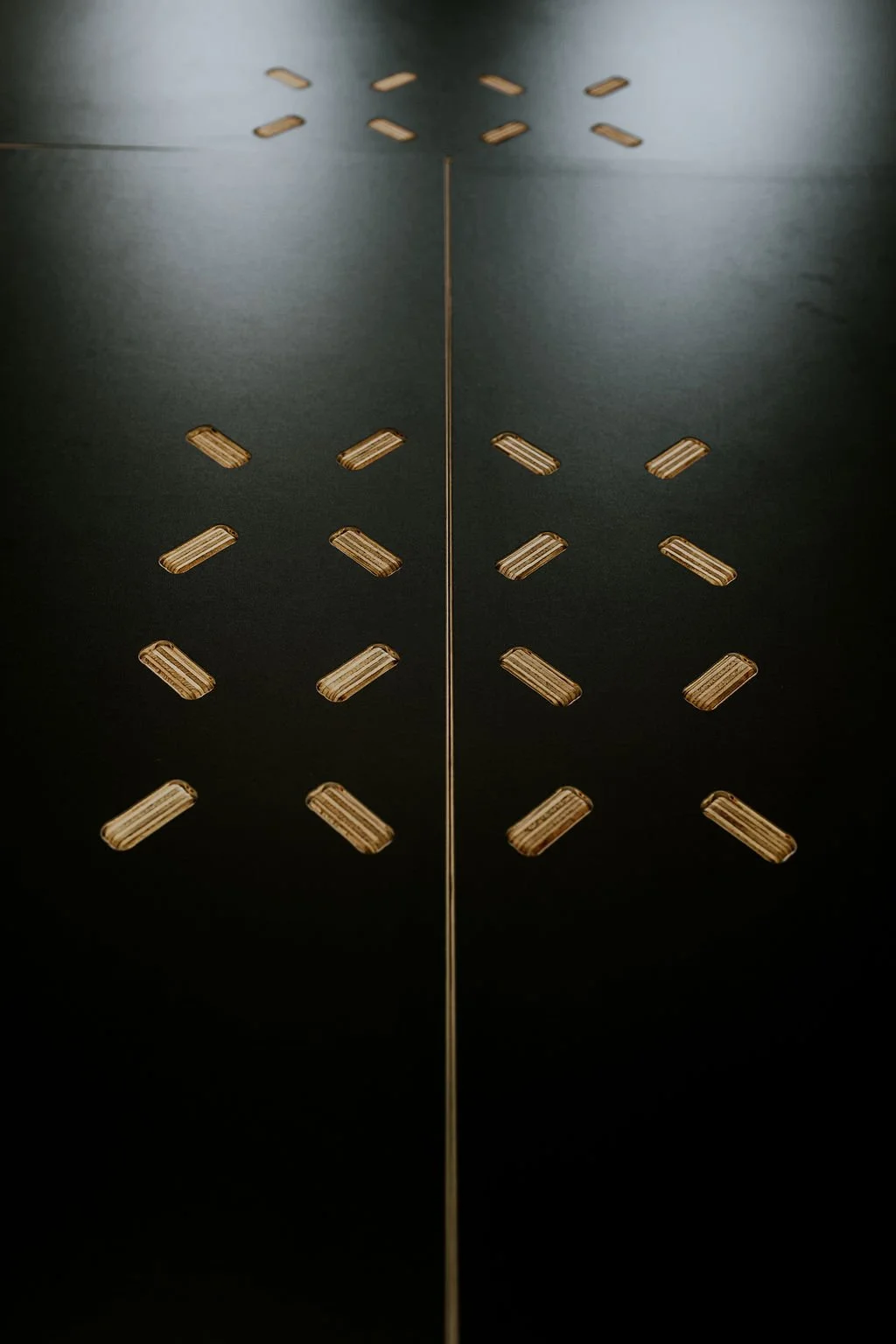 Top of a black table showing wood connection bits in a pattern.