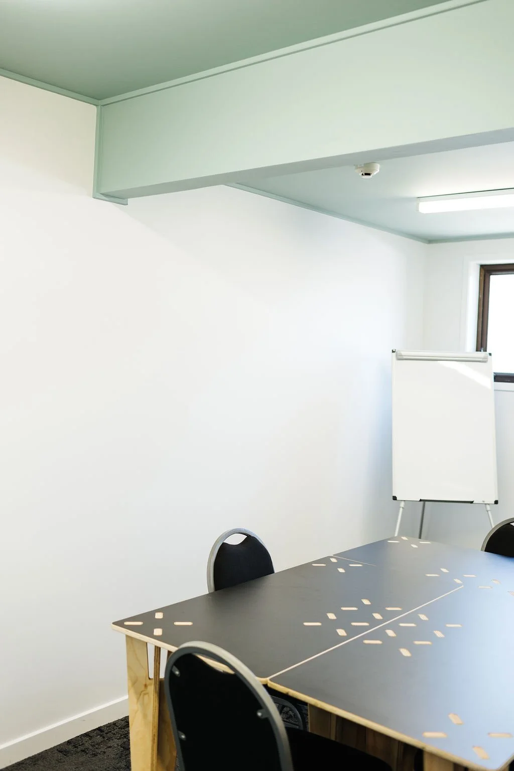 A white wall with a black table and black chairs in The Bureau, a meeting room at The Business Hive in Oamaru.