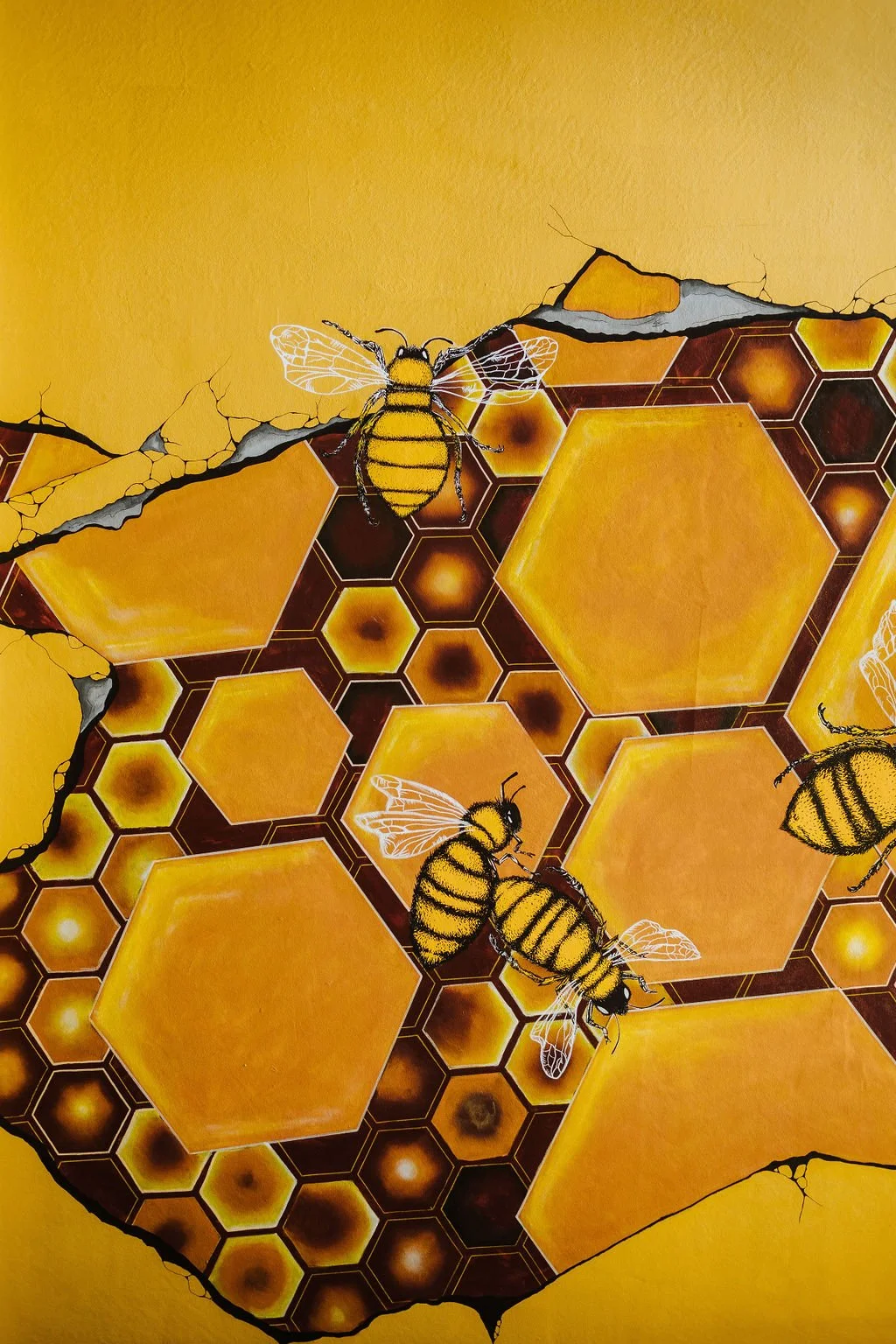 Bright yellow bee mural at The Business Hive coworking space with bees and a honeycomb