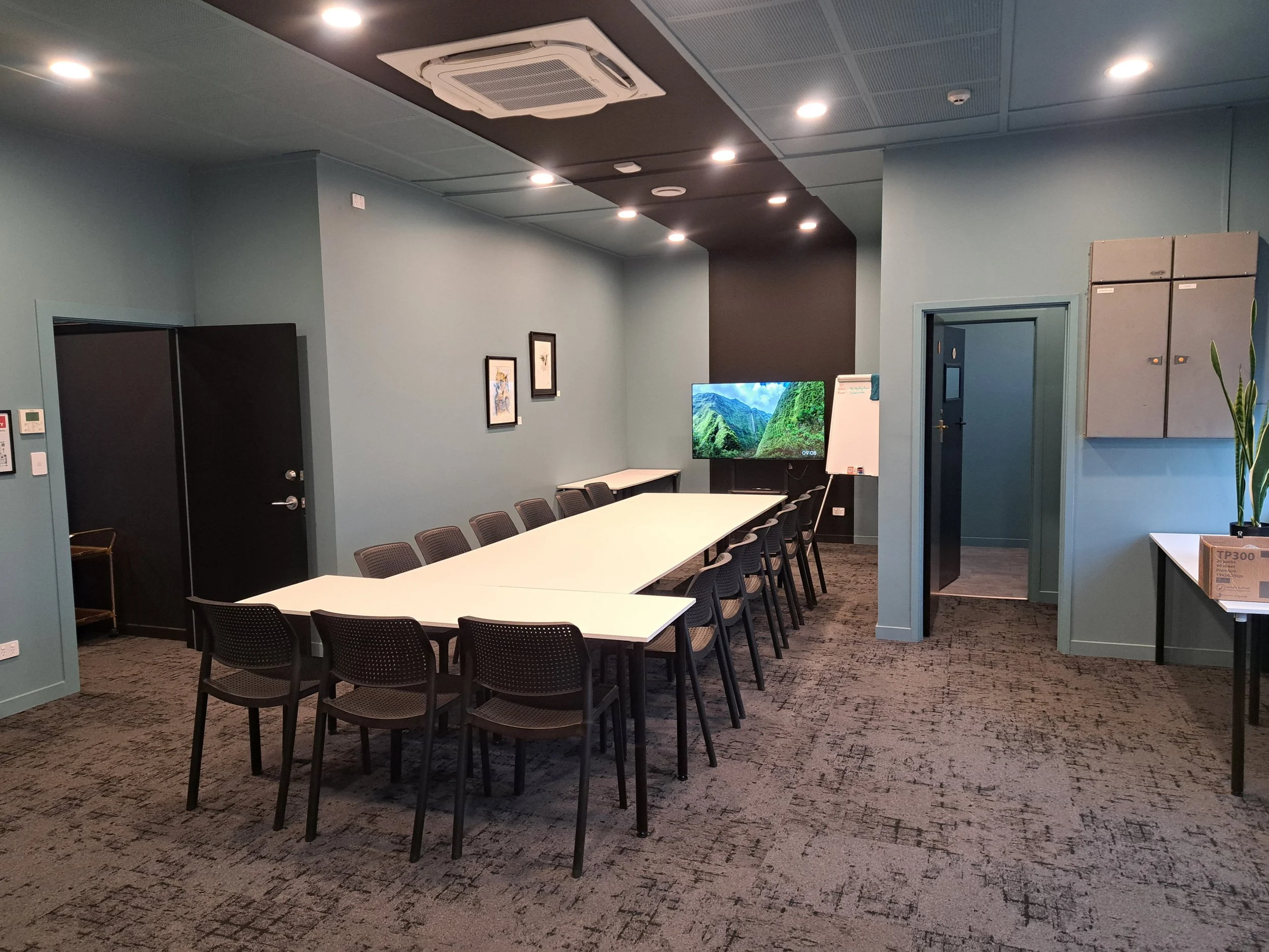 Brightly lit meeting and training room in Oamaru with a large white conference table, a flat screen TV against the wall, a small whiteboard and spotlights.