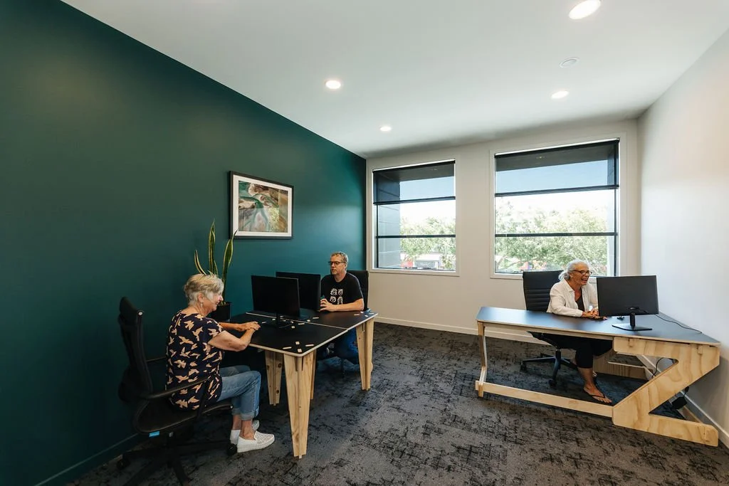 The Studio private office Oamaru with a teal and a white wall and three desks with one person sitting at each desk looking at a computer screen