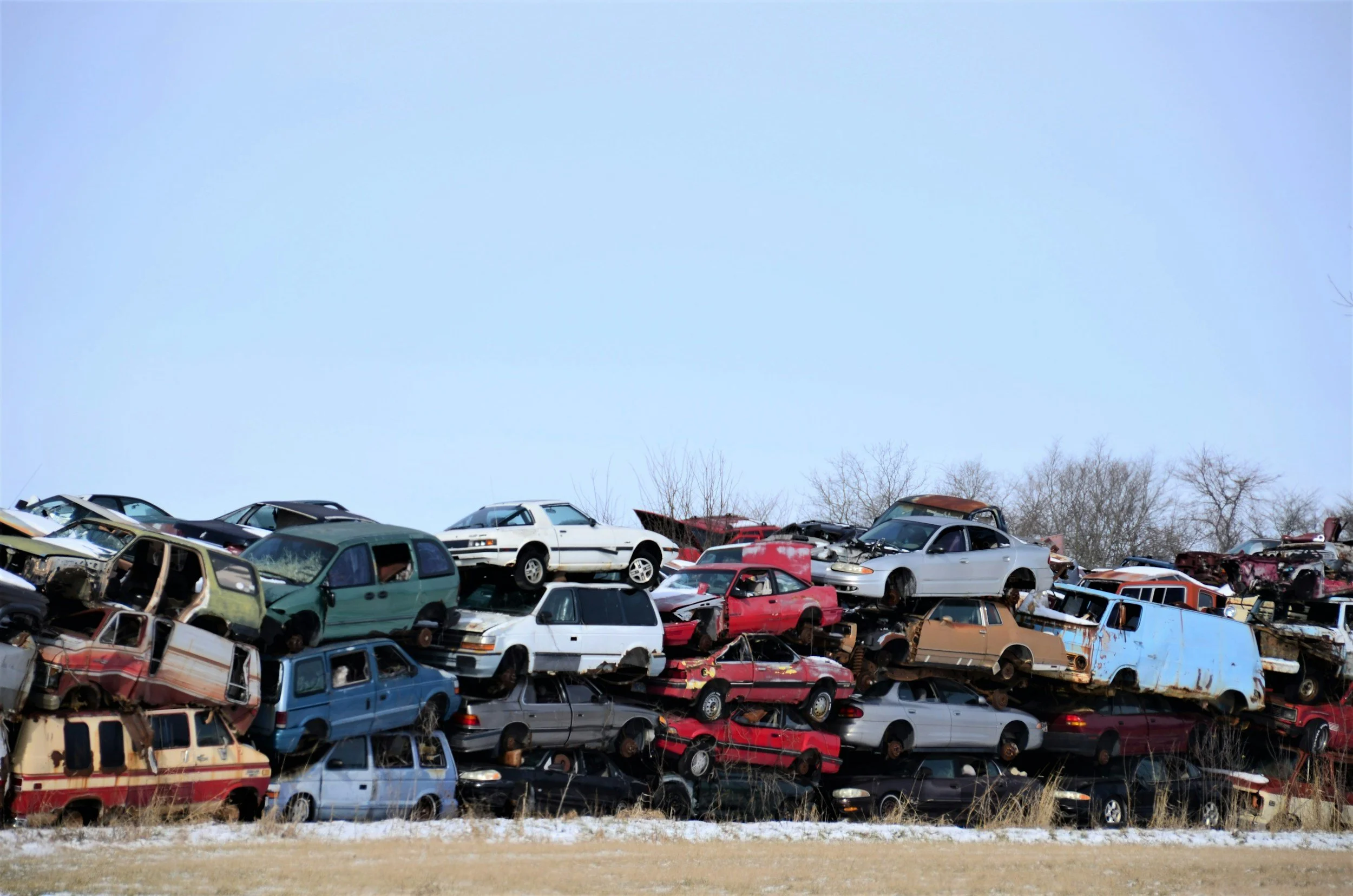 A large junkyard filled with stacked, wrecked and abandoned cars.