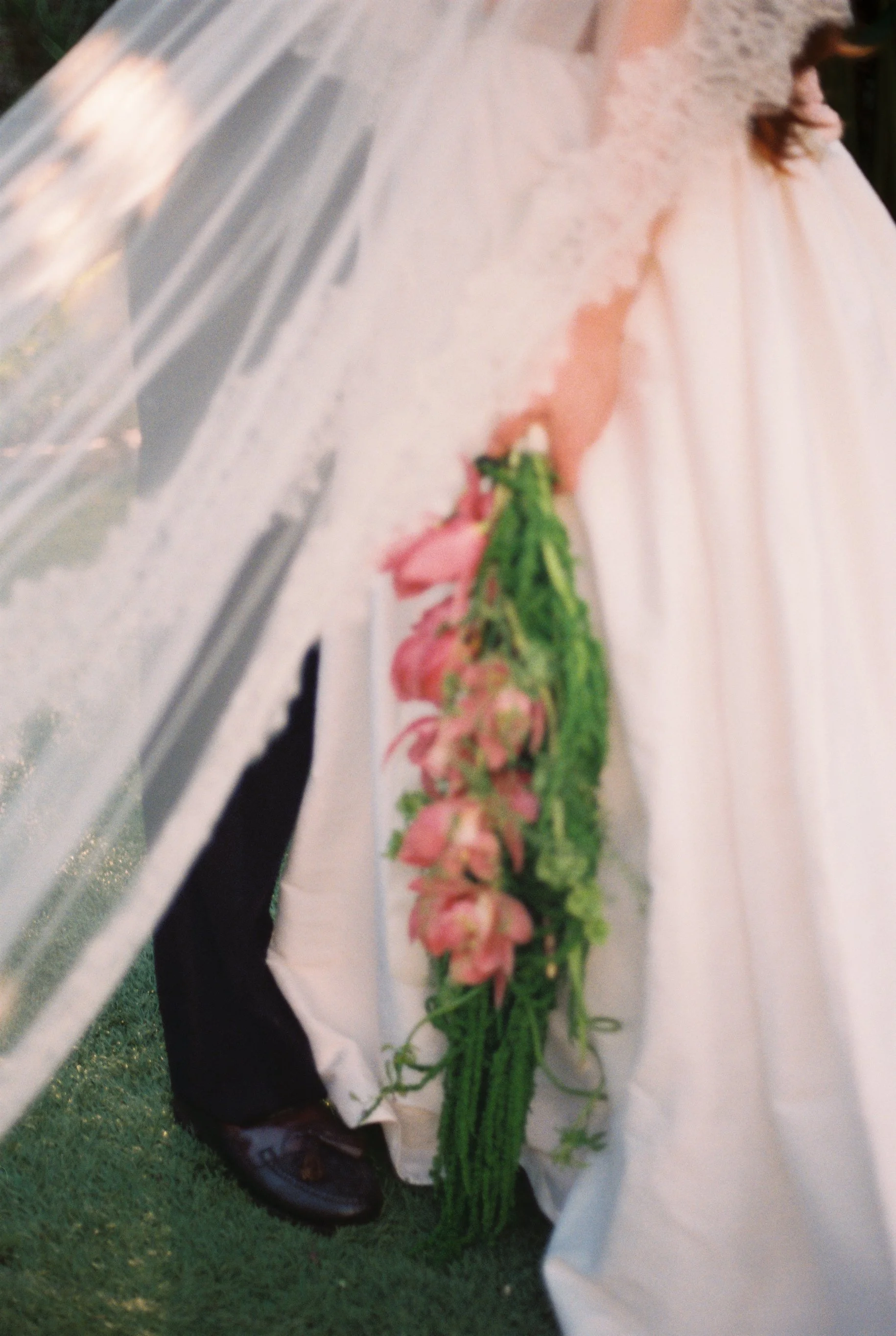 A bride in a wedding gown holding a bouquet of pink and green flowers.