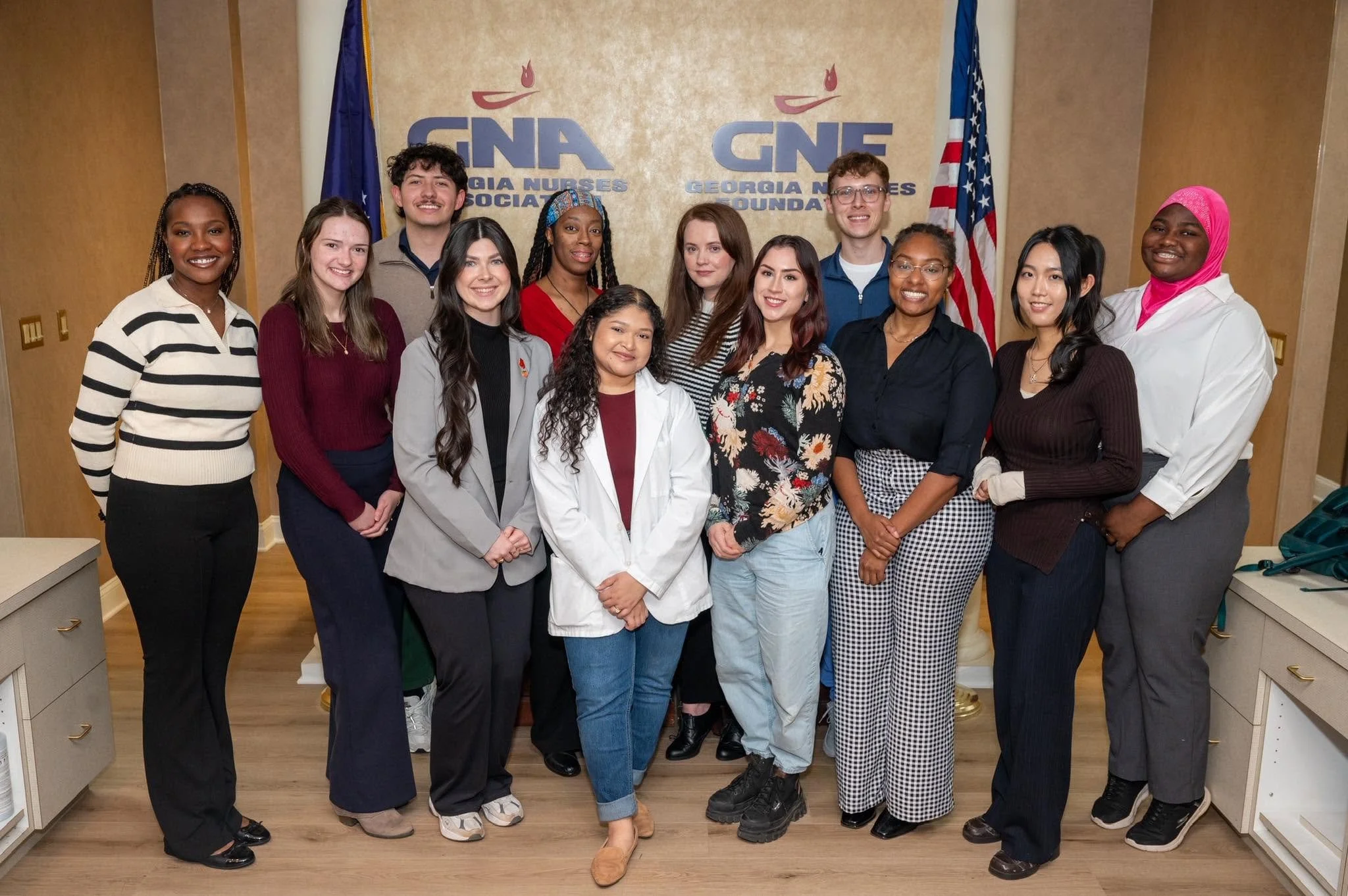 Group photo of diverse nurses and medical staff standing together in a hospital or healthcare setting, with Georgia Nurses Association logos and American flags in the background.