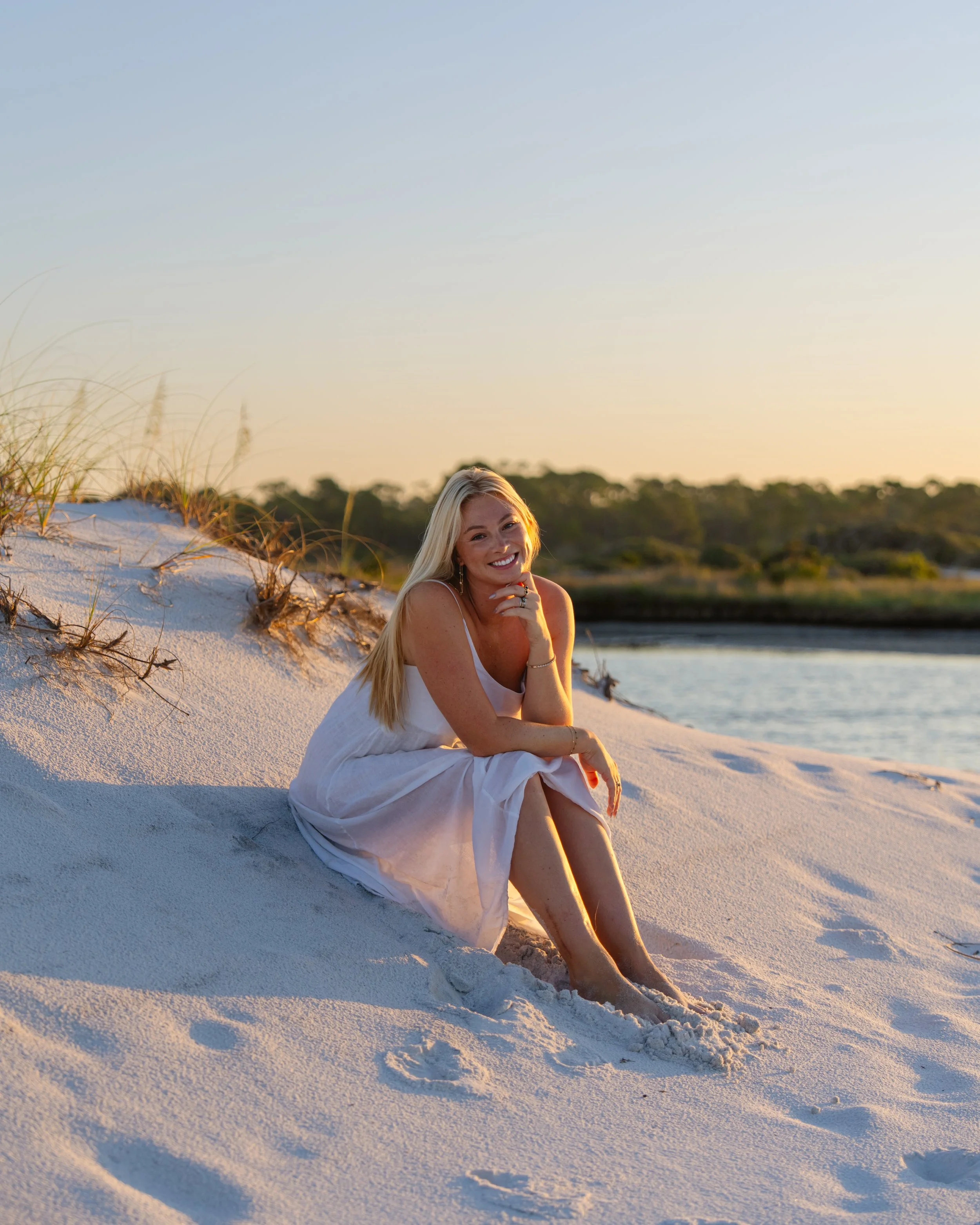 Portrait of a woman sitting on the dunes by the beach with the sunrise behind her. Grayton Beach Photographer. 30A Photographer