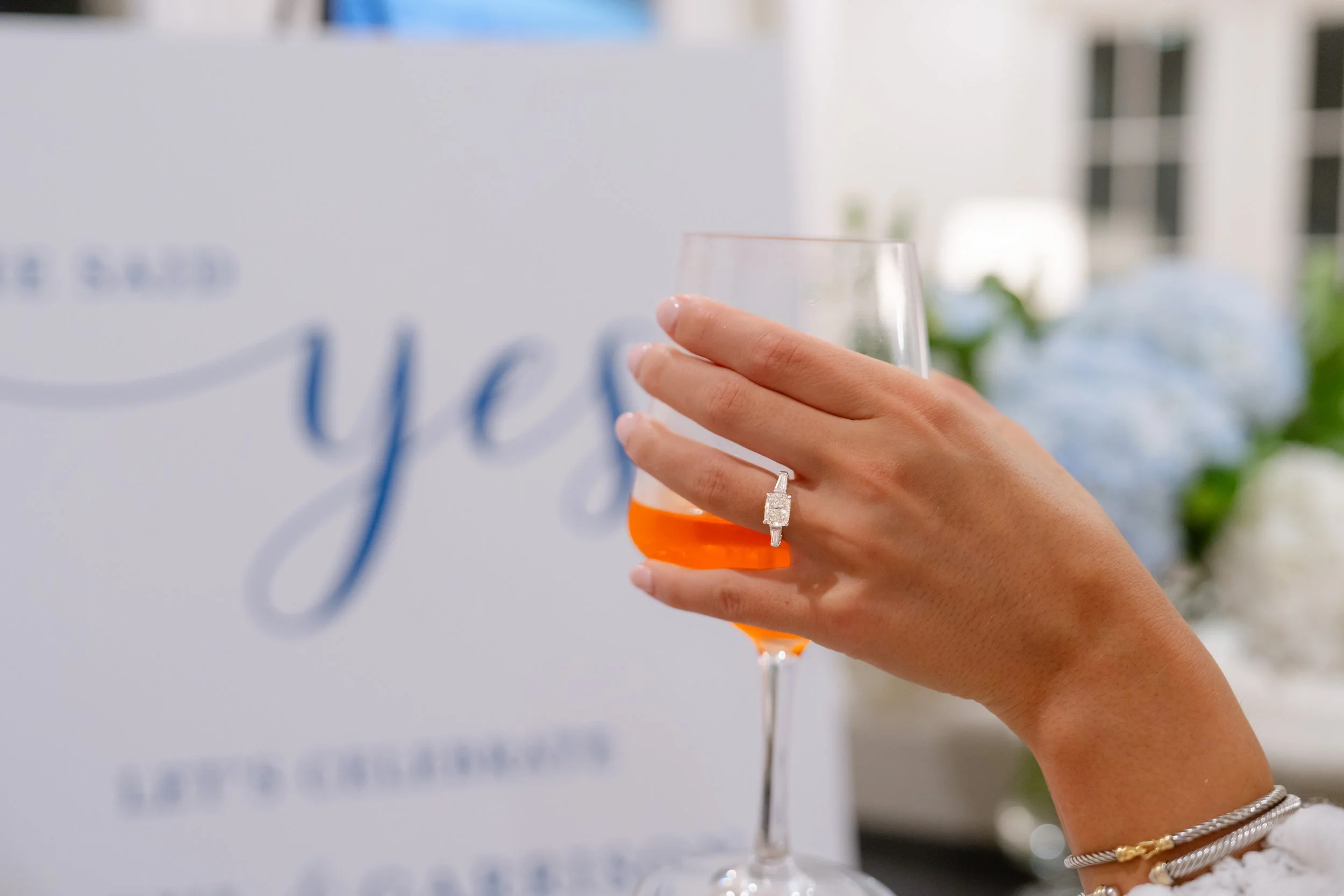 Woman holding a glass of champagne showcasing her engagement ring. 30A Photographer. 30A Engagement Photographer