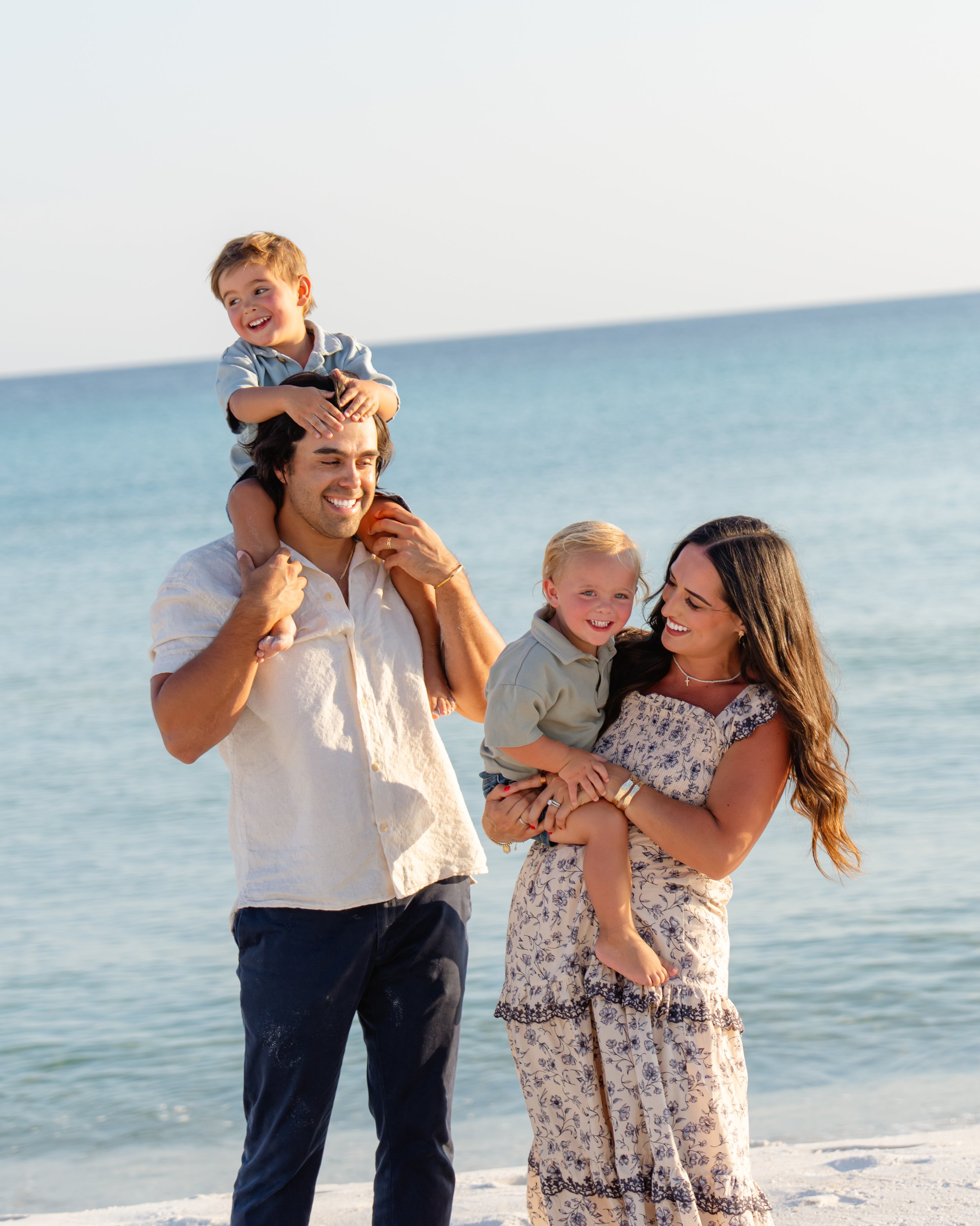 Family of four on the beach laughing and smiling.